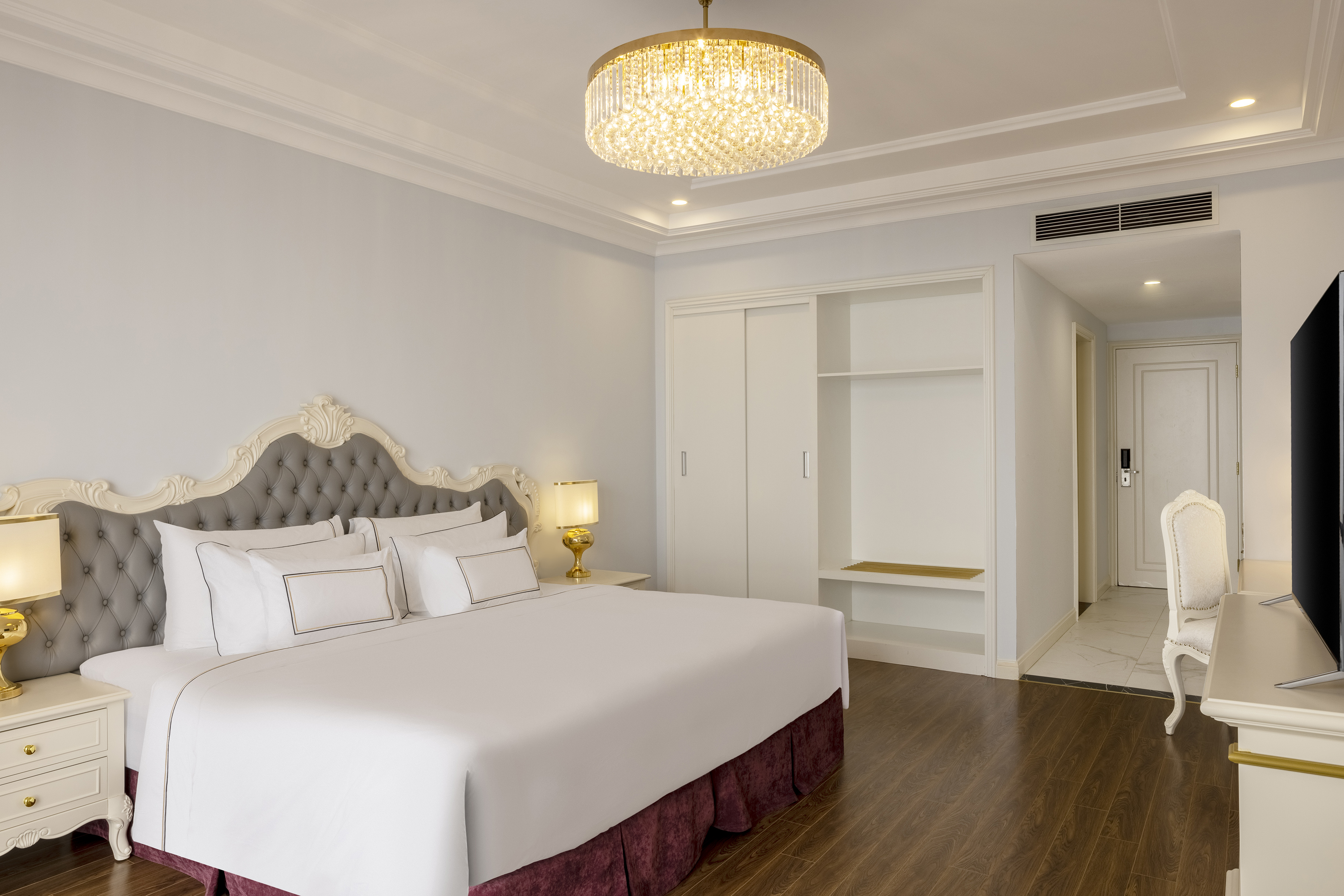 Luxury bedroom with elegant bed, tufted headboard, and chandelier.