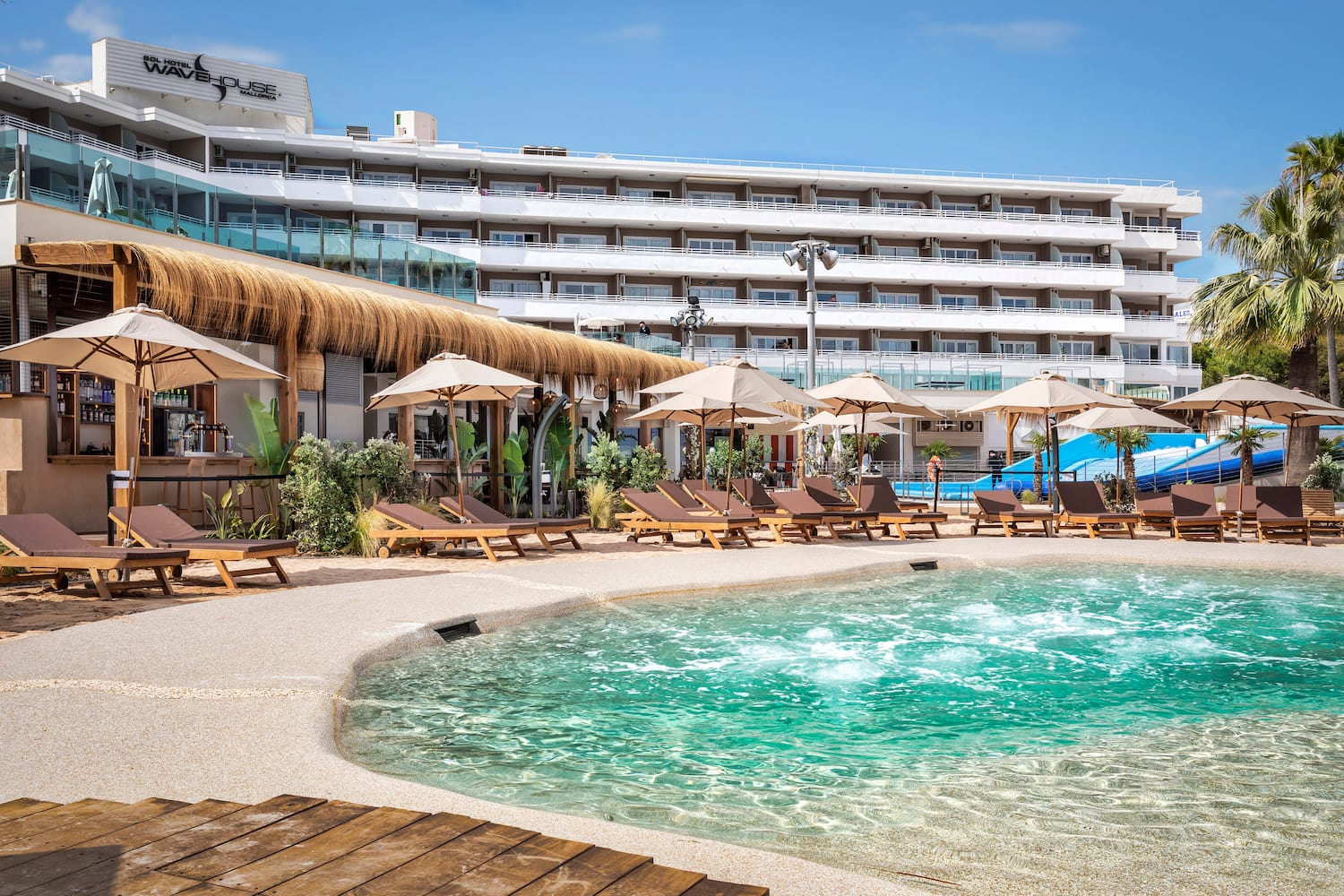 a pool with umbrellas and chairs in front of a hotel