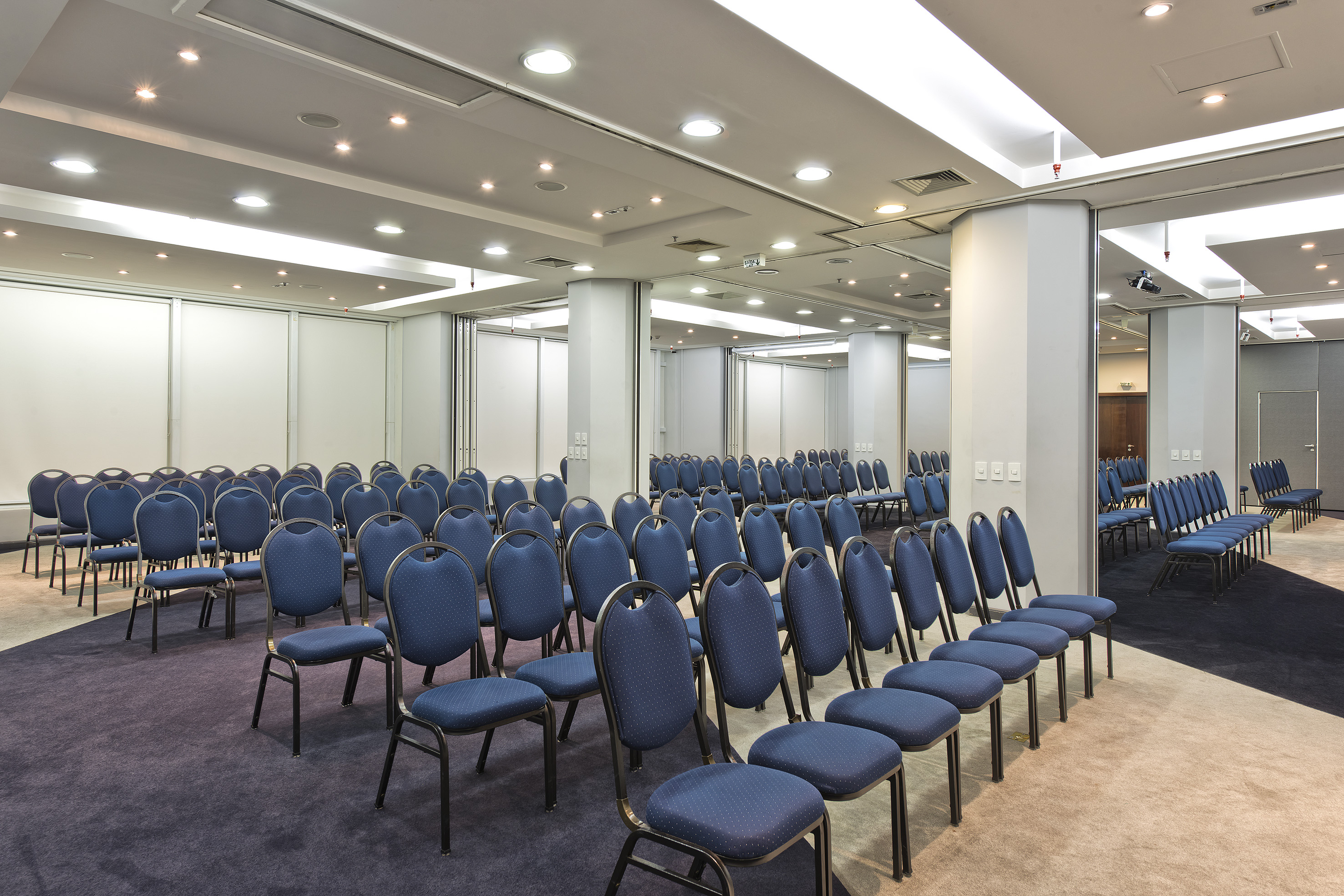 Empty modern conference room with blue chairs, projector, and plush carpet.
