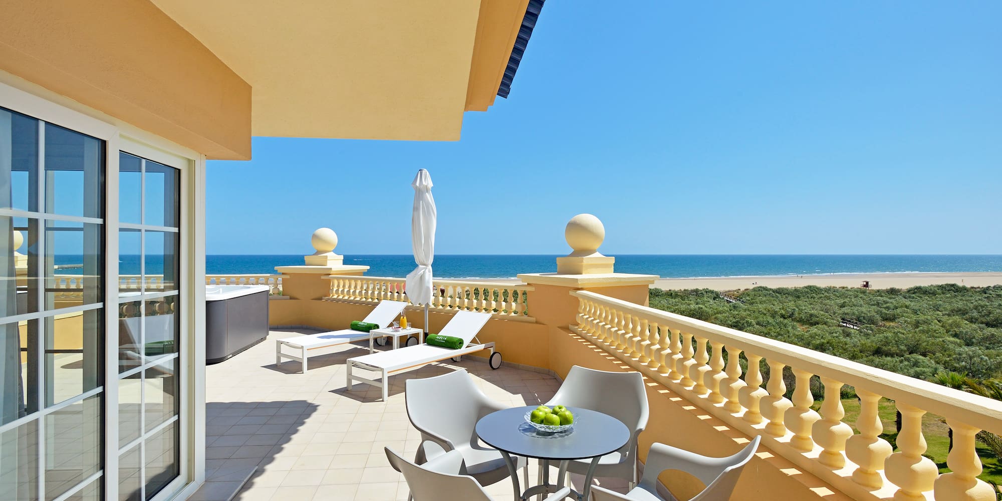 a patio with chairs and a table on a balcony overlooking the ocean