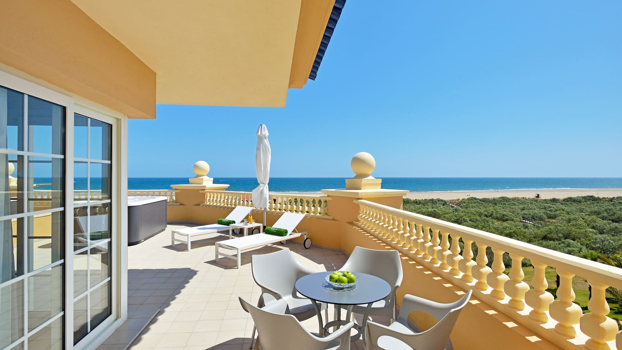 a patio with chairs and a table on a balcony overlooking the ocean