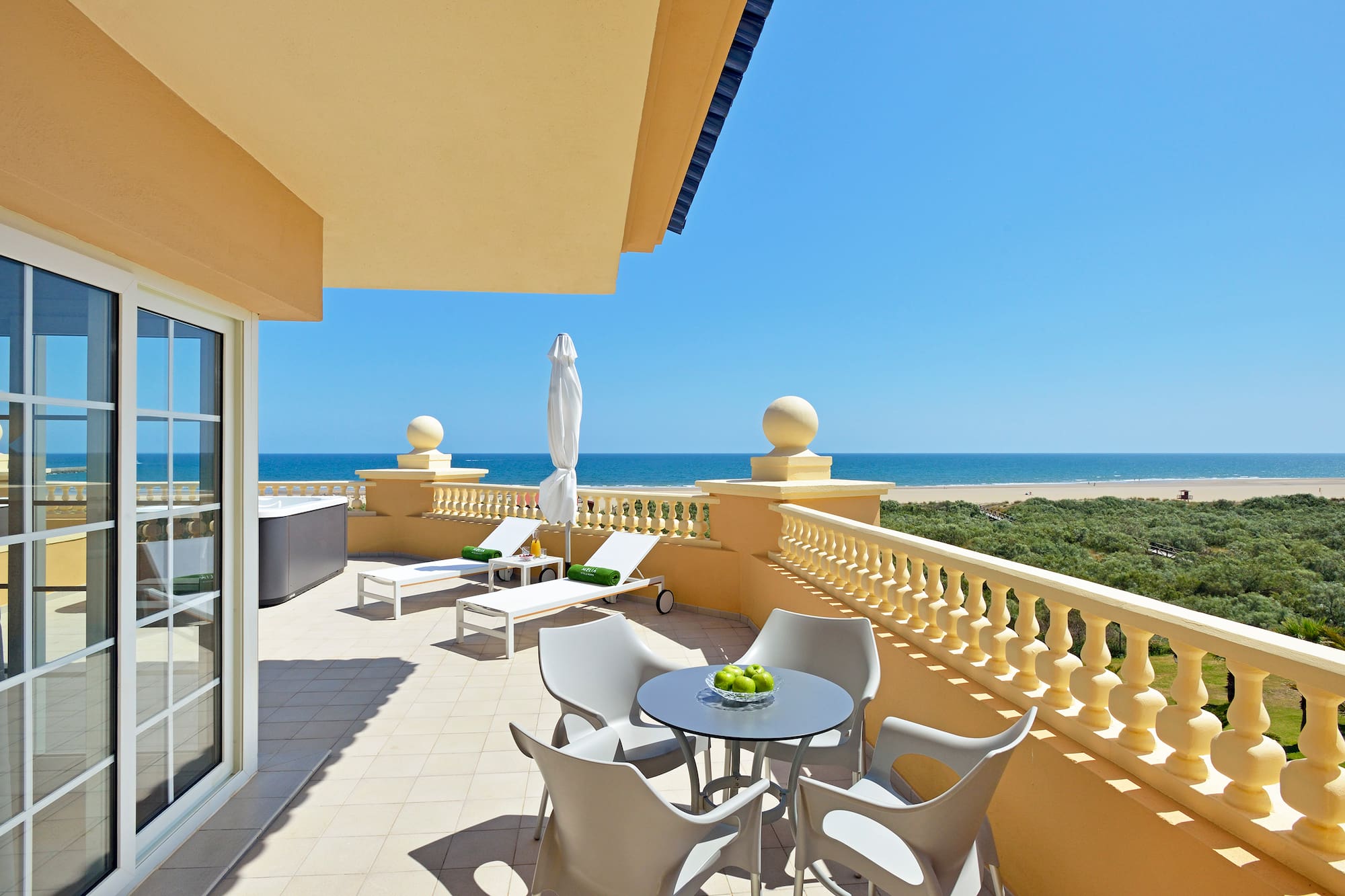 a patio with chairs and a table on a balcony overlooking the ocean