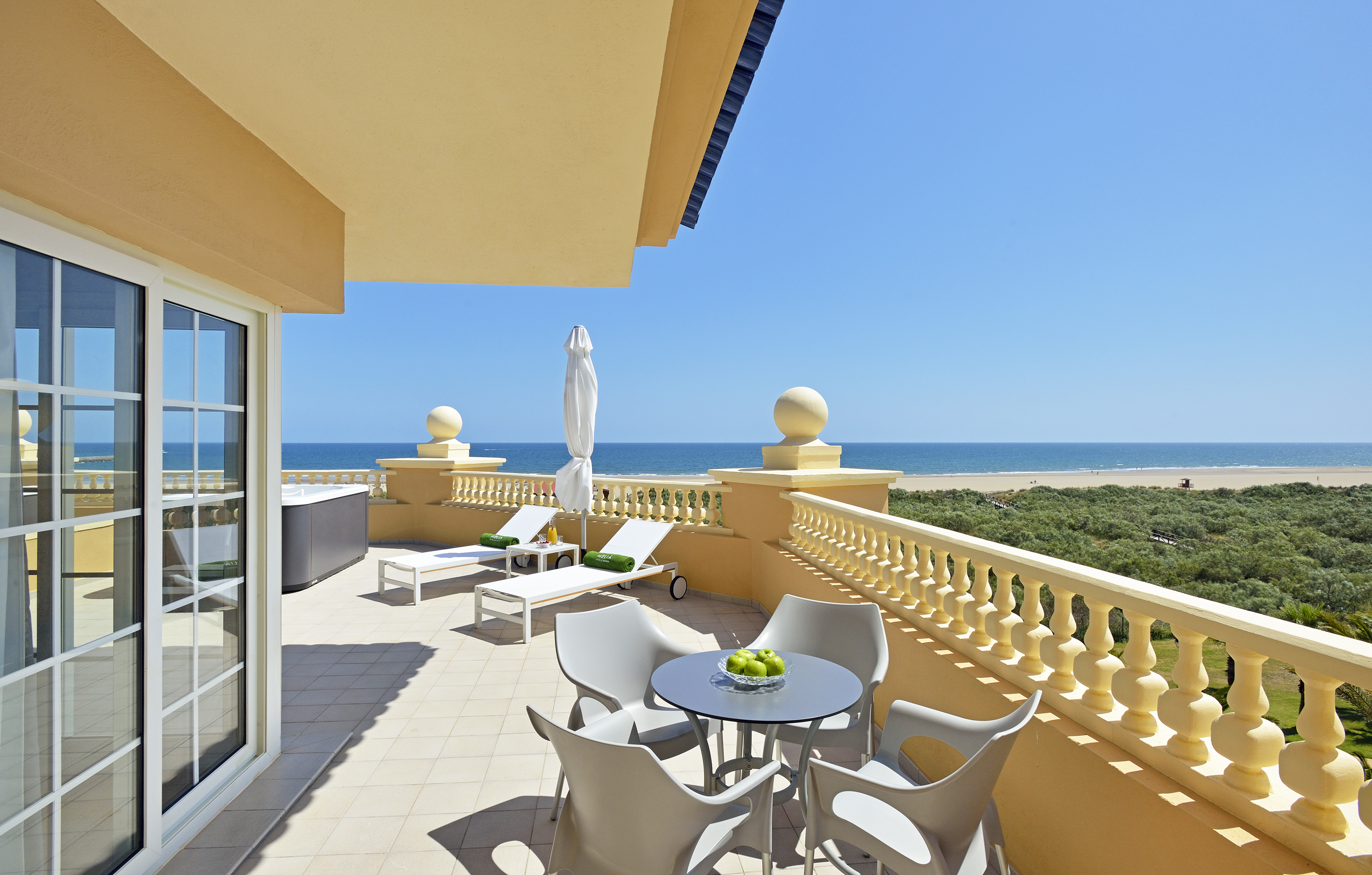a patio with chairs and a table on a balcony overlooking the ocean