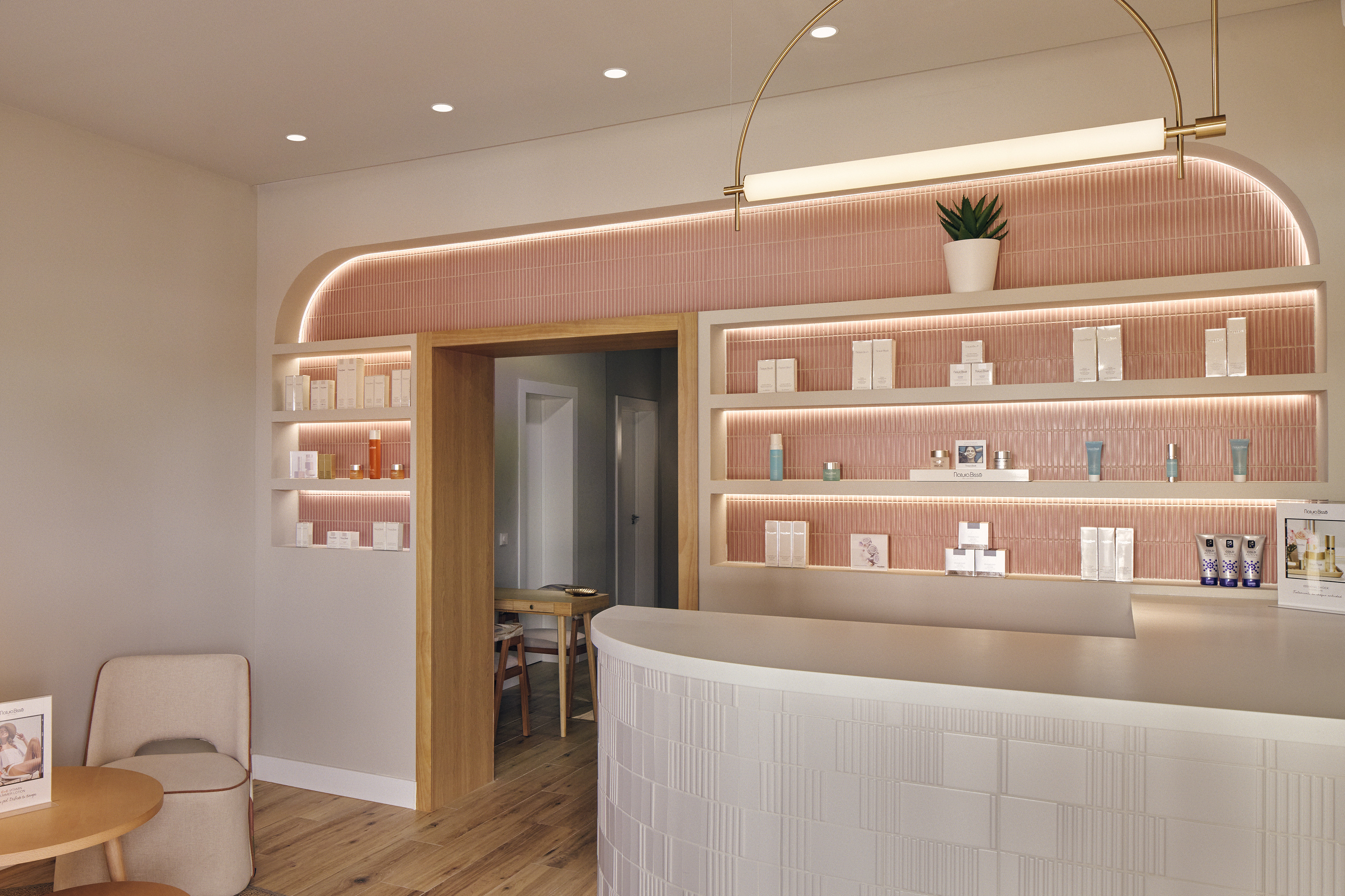 Elegant beauty salon reception with pink tiled wall and skincare product display.