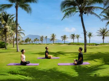 people sitting on mats in a park.