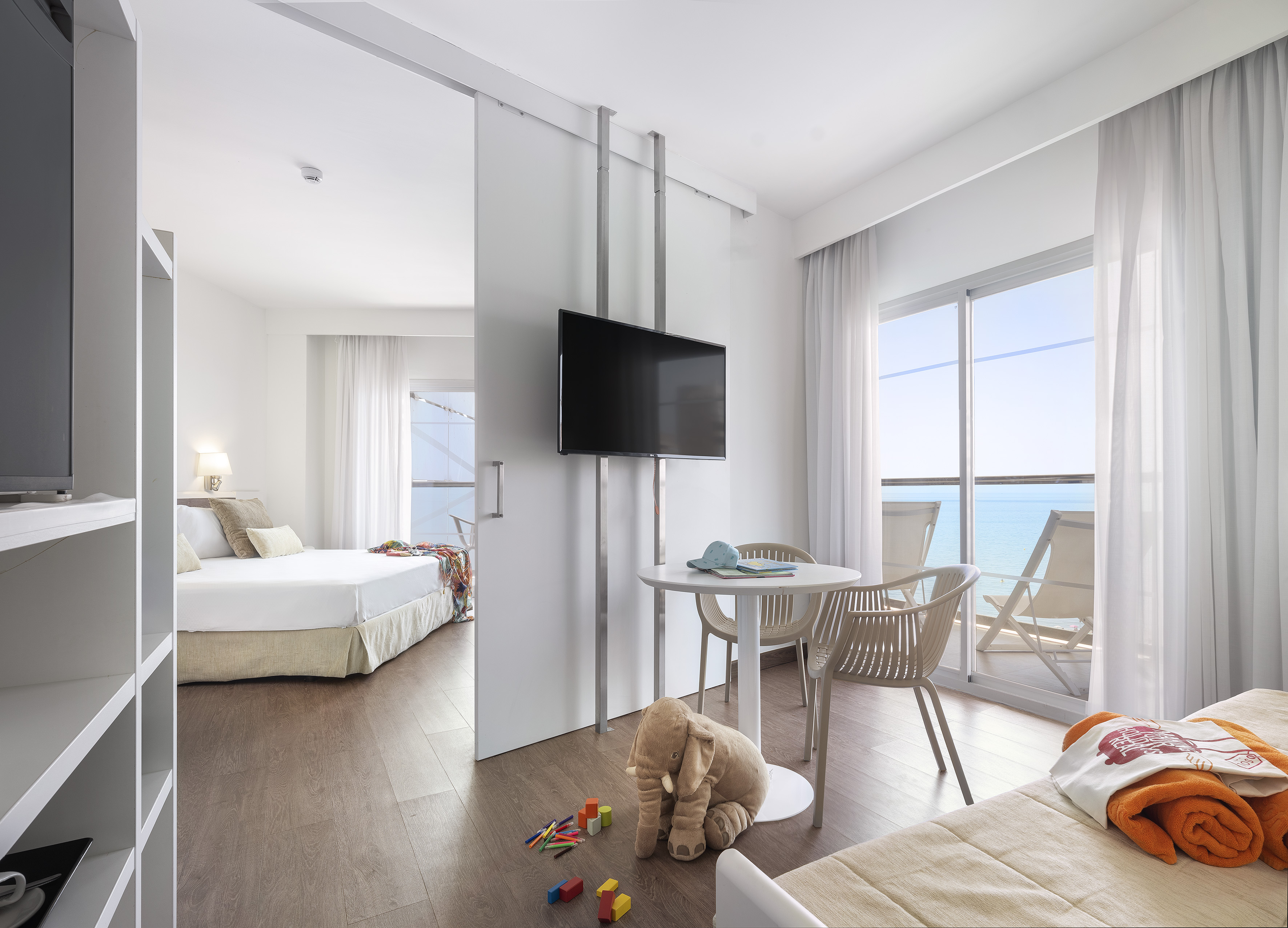 Modern hotel suite with ocean view balcony, separate bedroom and living area.