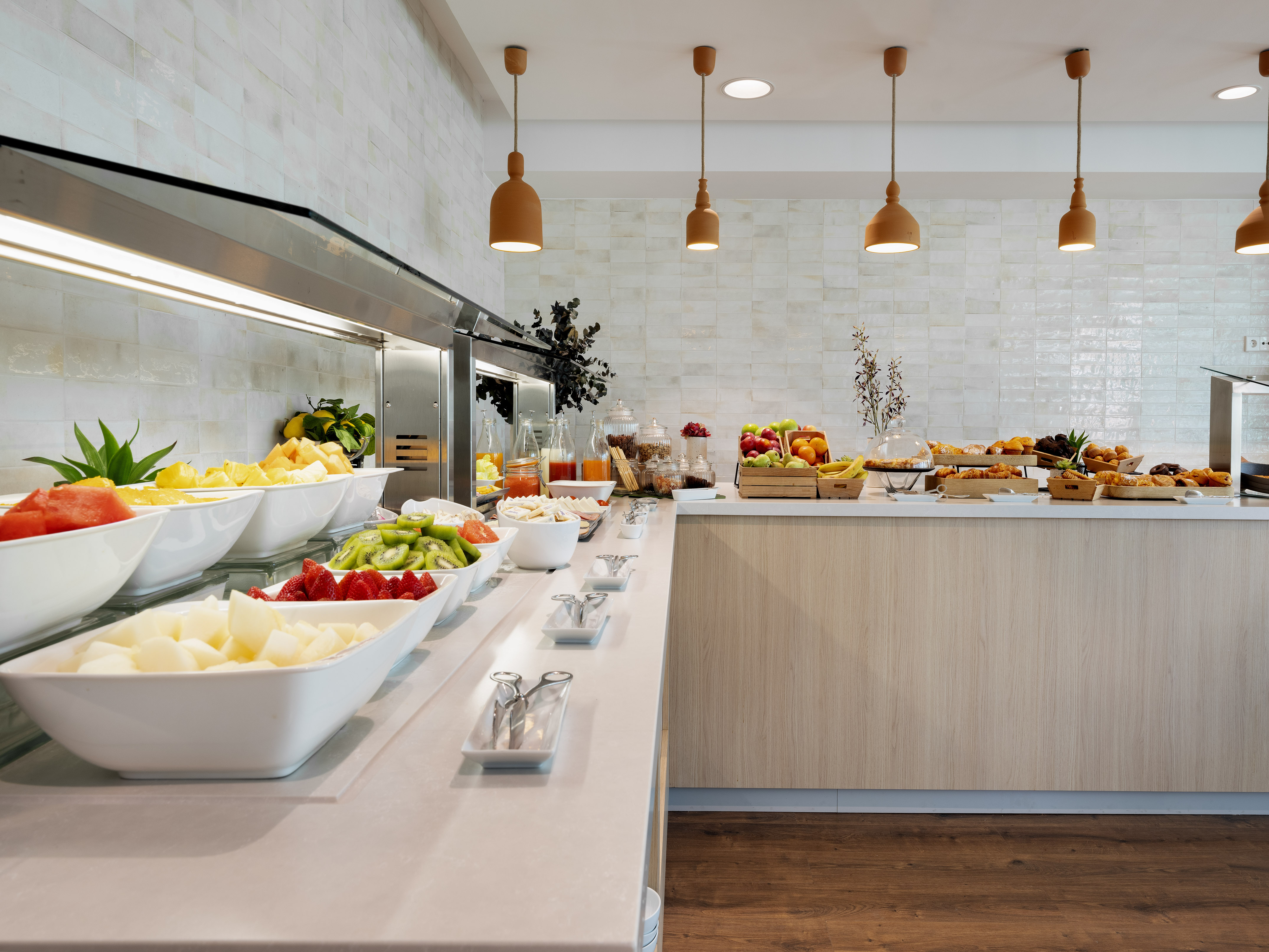 Buffet breakfast with fresh fruit, pastries, and juices in a modern hotel.