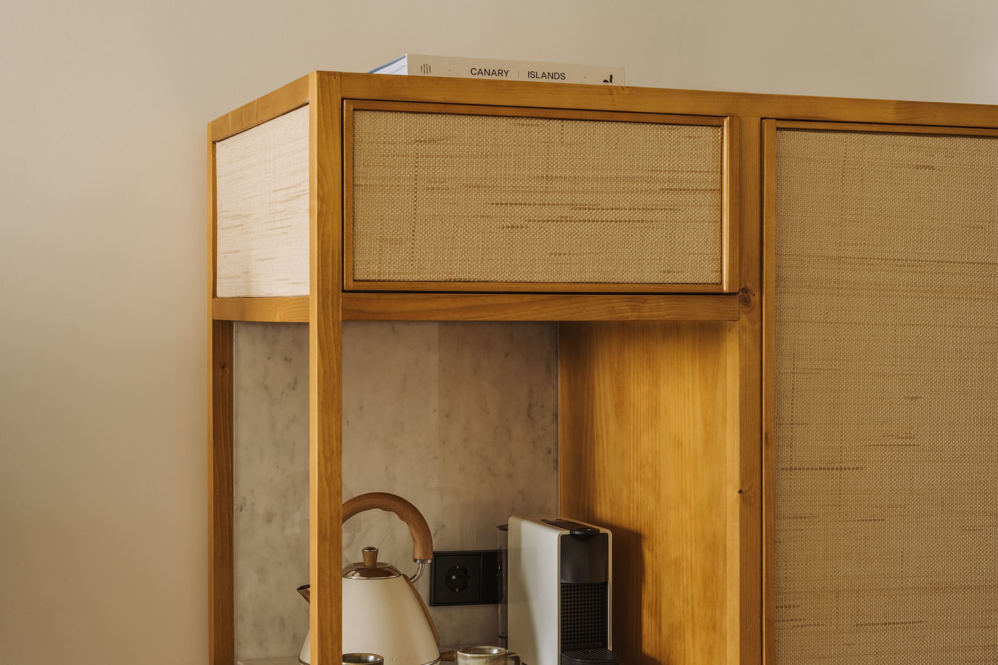 a cabinet with a tea kettle and coffee cups on top