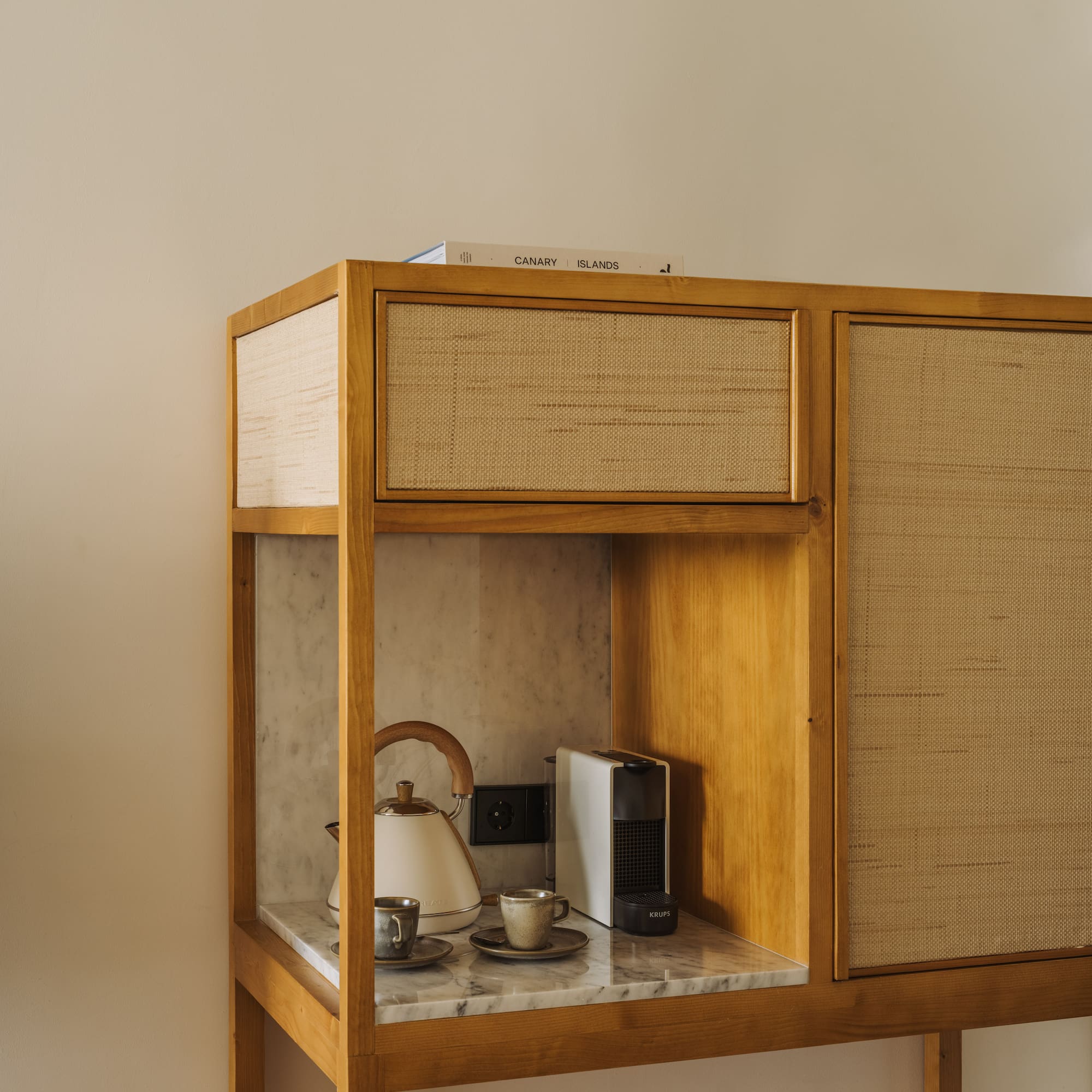 a cabinet with a tea kettle and coffee cups on top