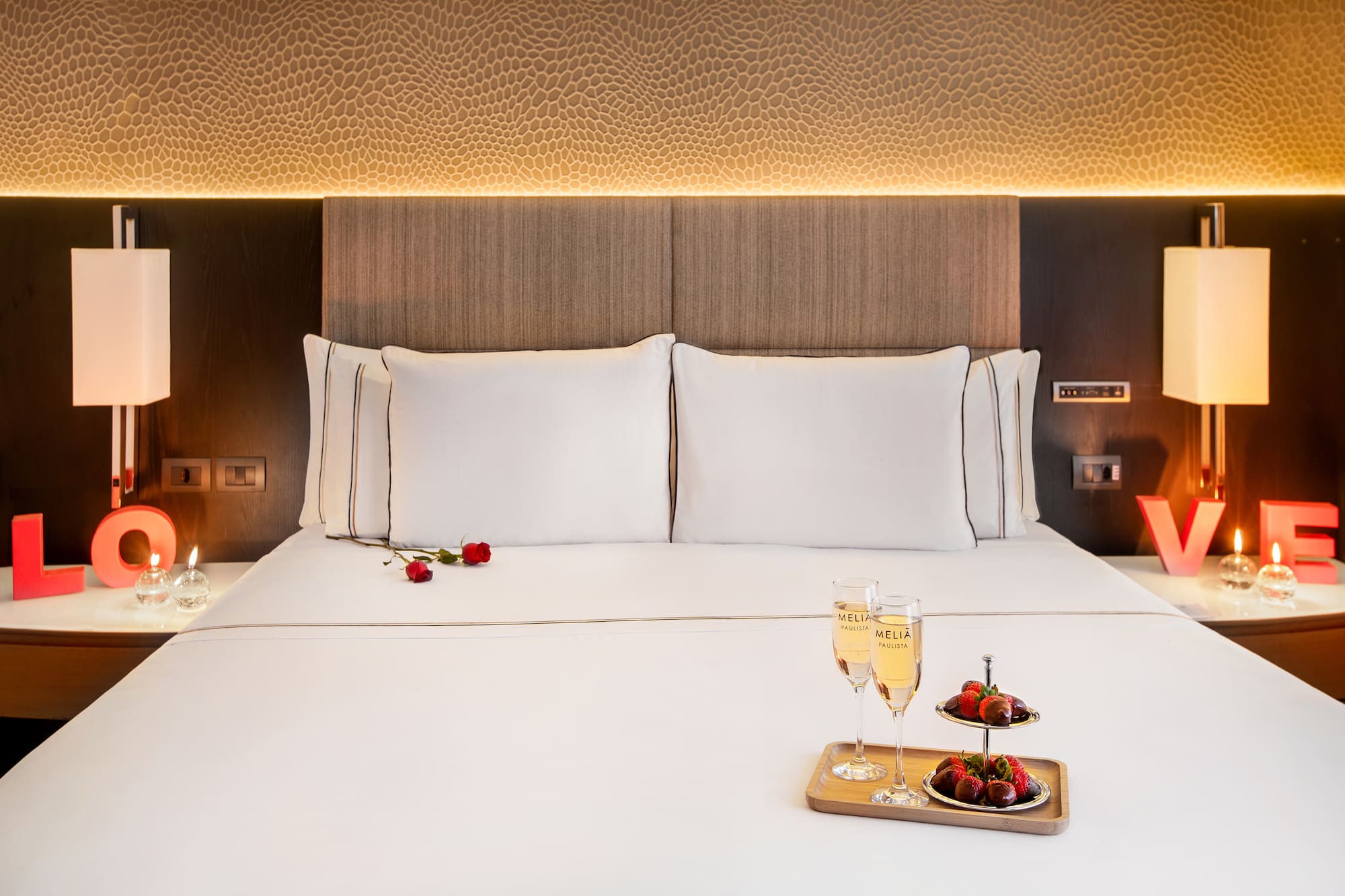 a bed with a tray of champagne and strawberries