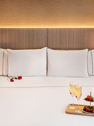 a bed with a tray of champagne and strawberries