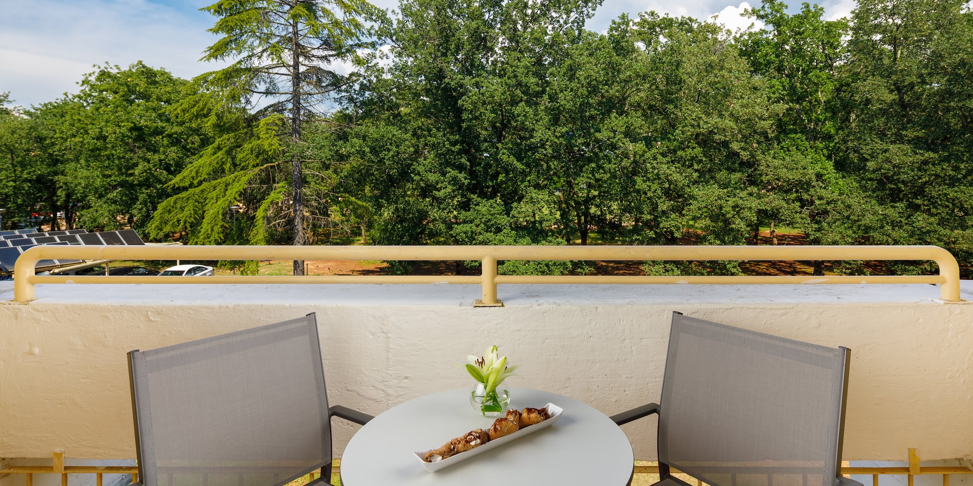 a table with a tray of food on it and chairs on a balcony