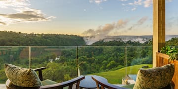 a balcony with a view of a forest and a river