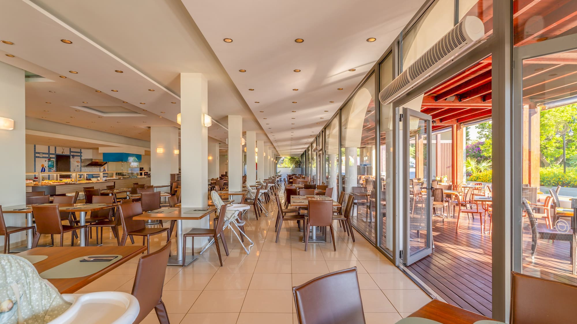 Spacious resort restaurant with buffet, indoor tables, and sunny outdoor terrace.