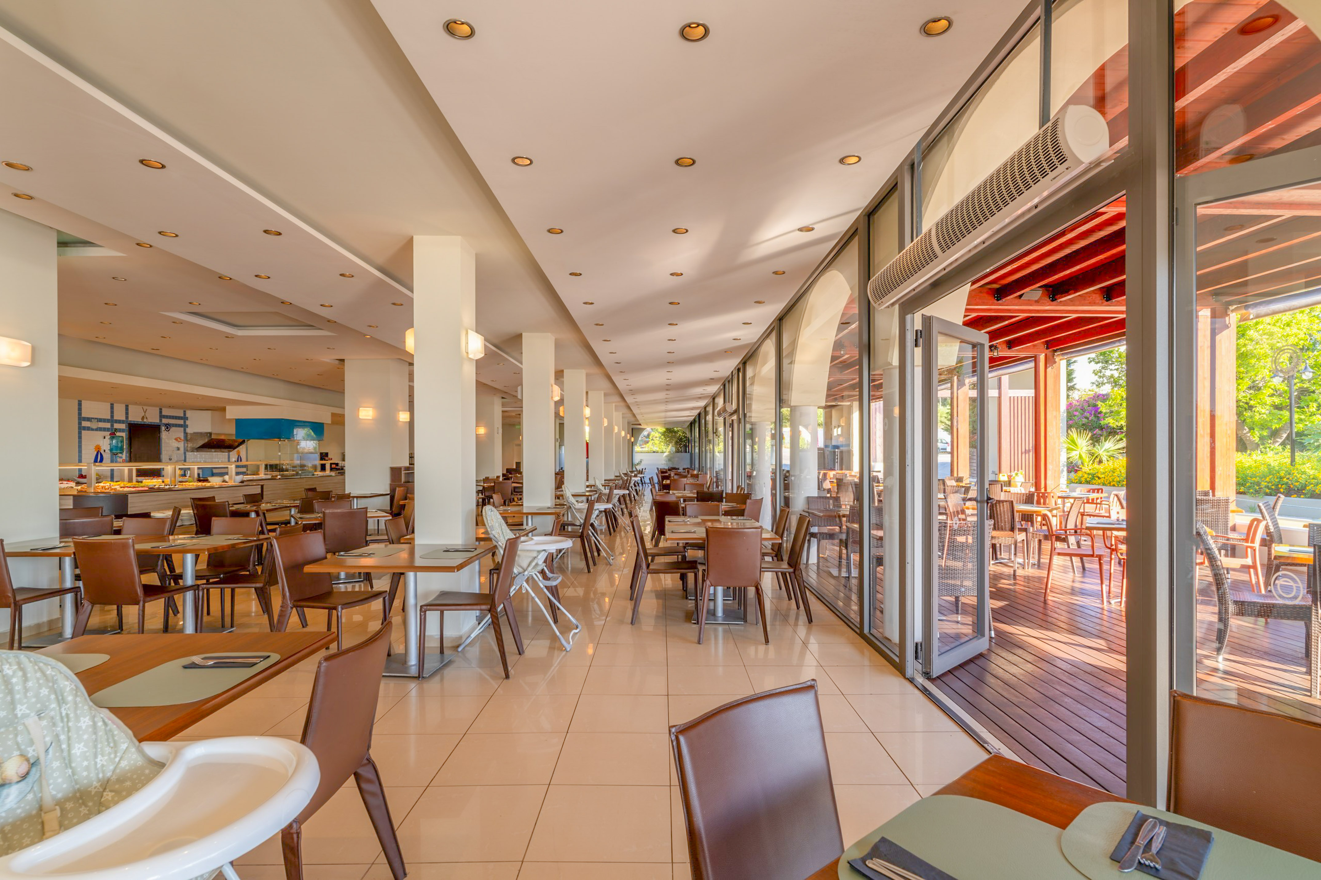 Spacious resort restaurant with buffet, indoor tables, and sunny outdoor terrace.