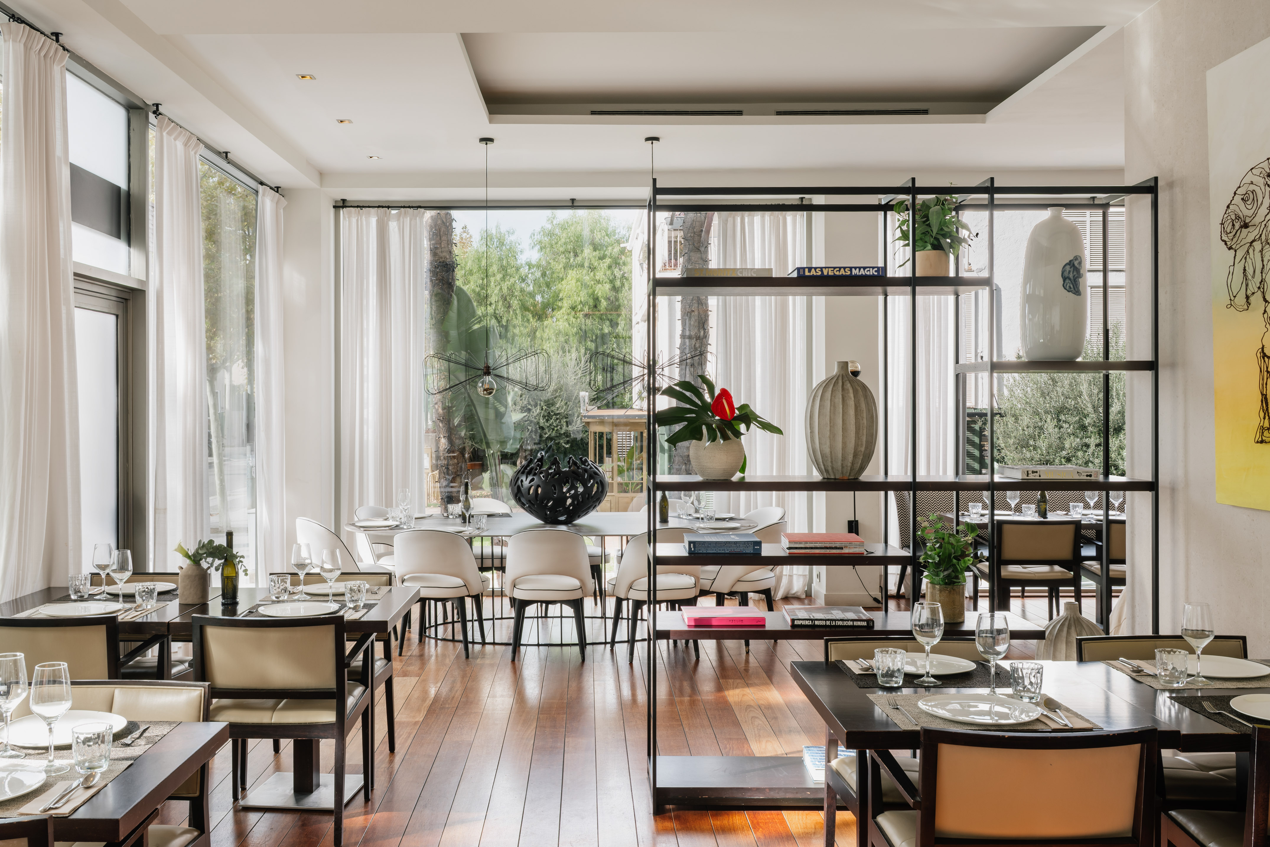 Modern restaurant with set tables, large windows, and decorative shelving.