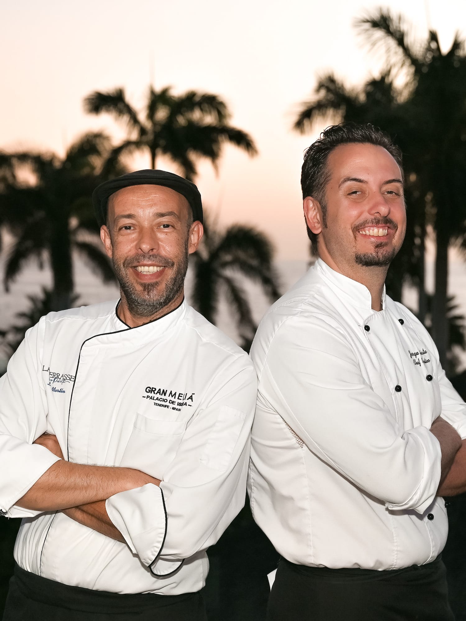 two men standing back to back smiling