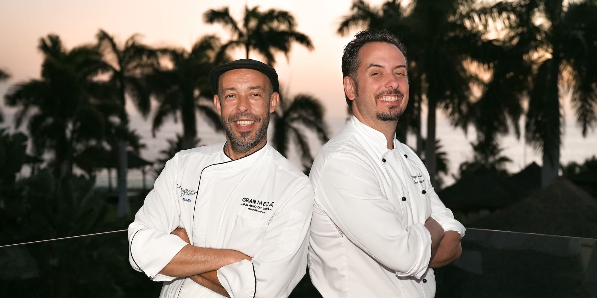 two men standing back to back smiling