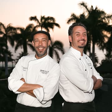 two men standing back to back smiling