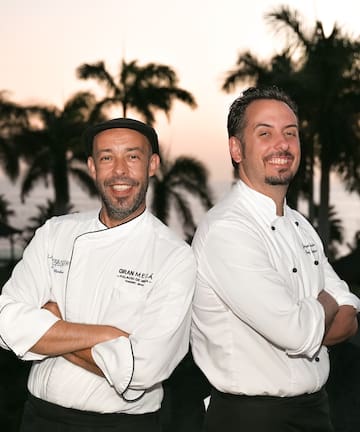 two men standing back to back smiling