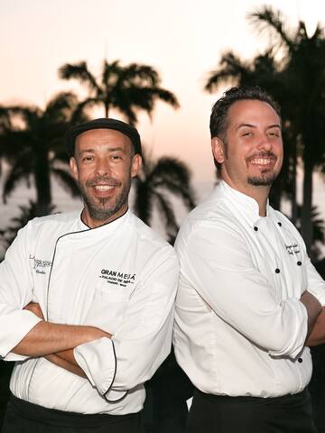two men standing back to back smiling