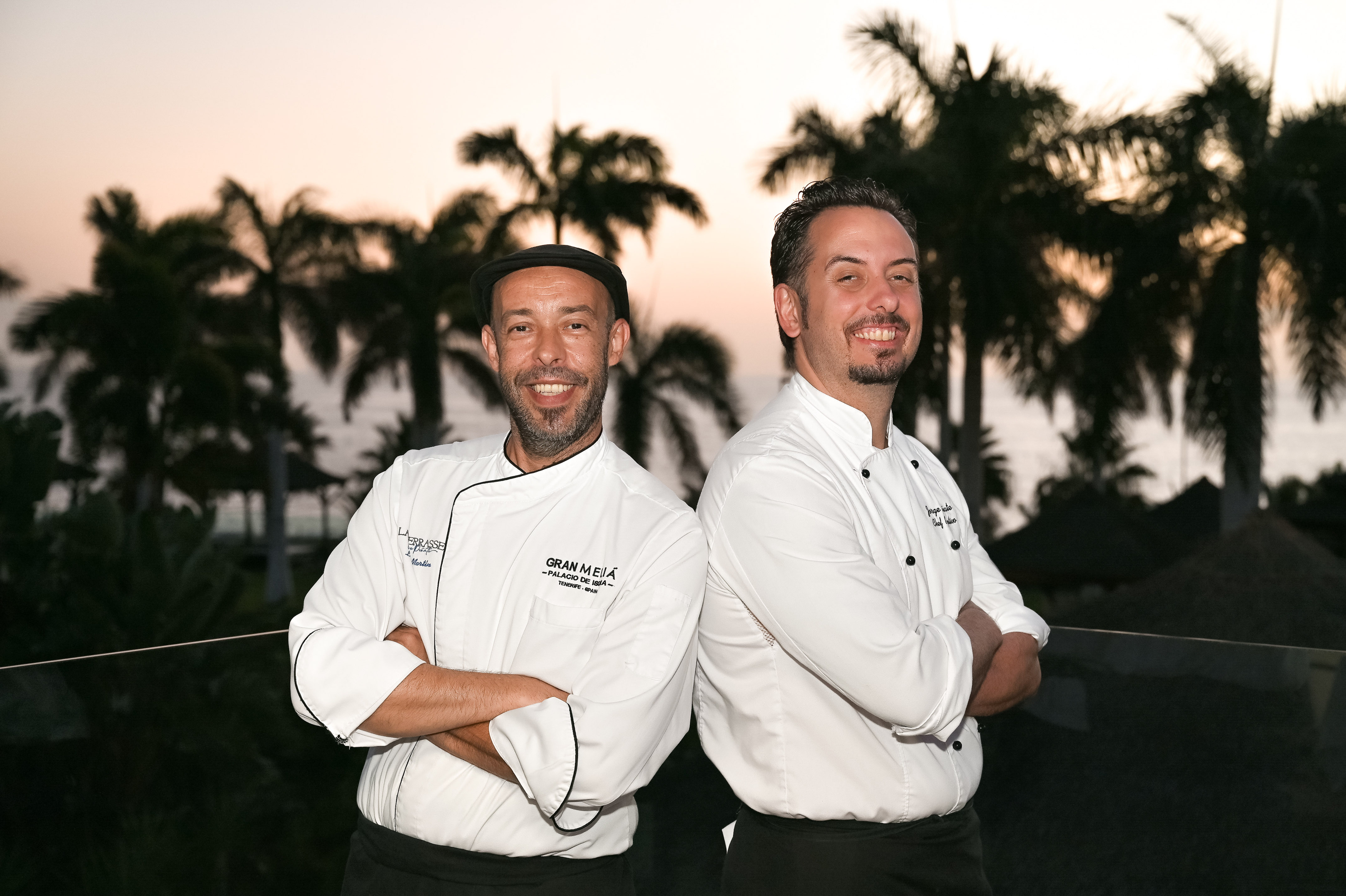 two men standing back to back smiling