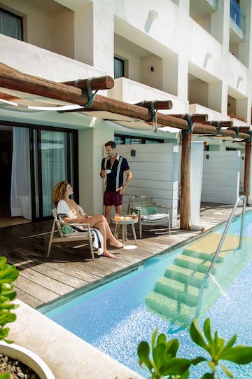 a man and woman sitting on a chair by a pool