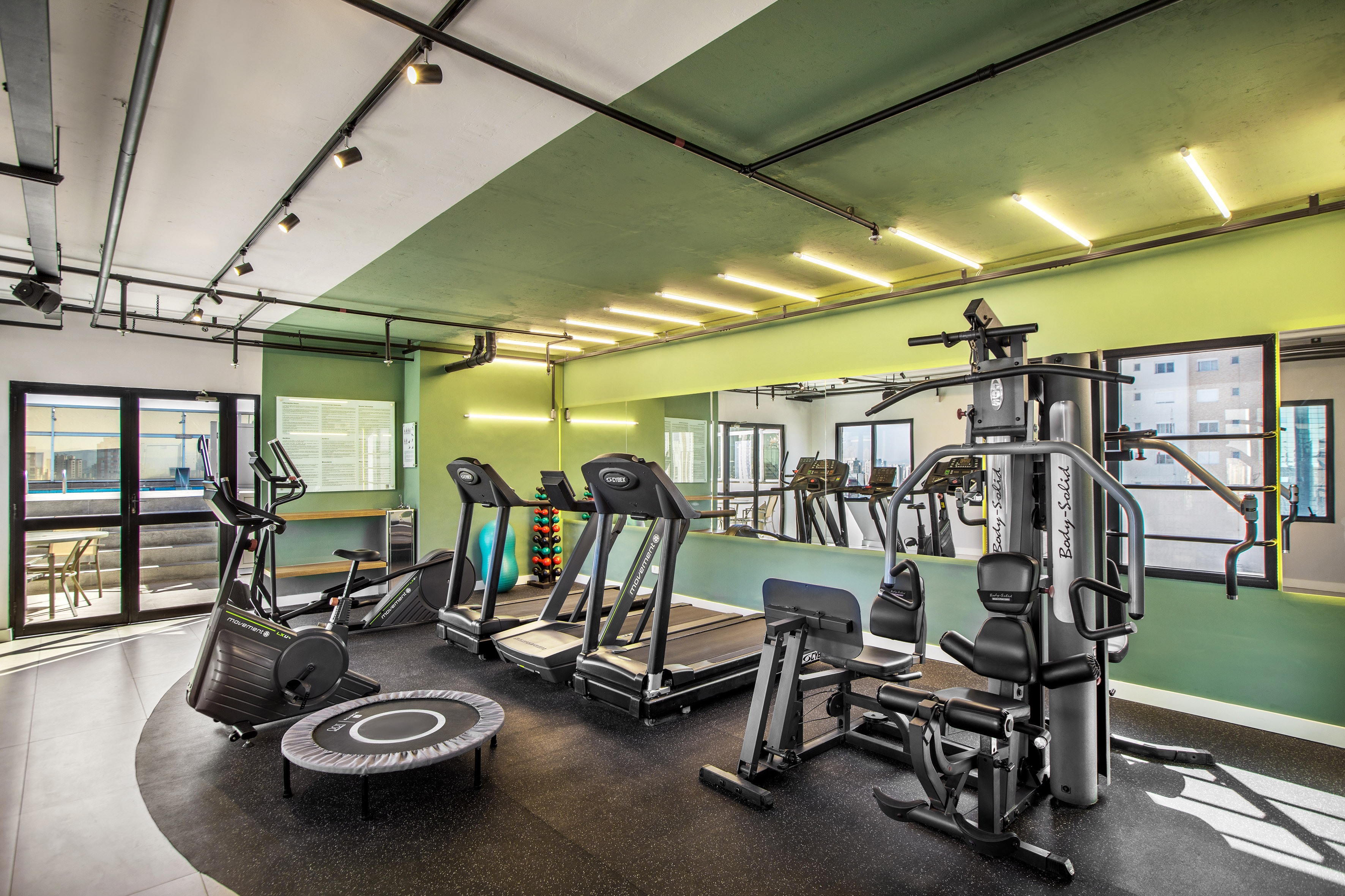 Modern gym with treadmills, exercise bike, and weight training equipment.