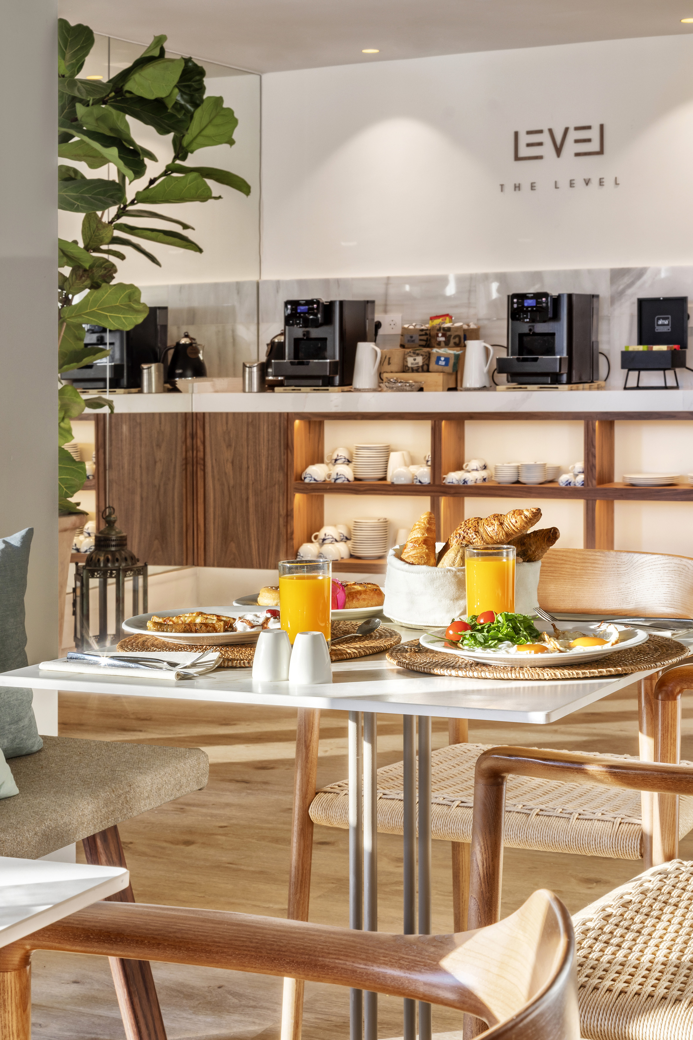 Set breakfast table in modern hotel dining area with orange juice, eggs, pastries.