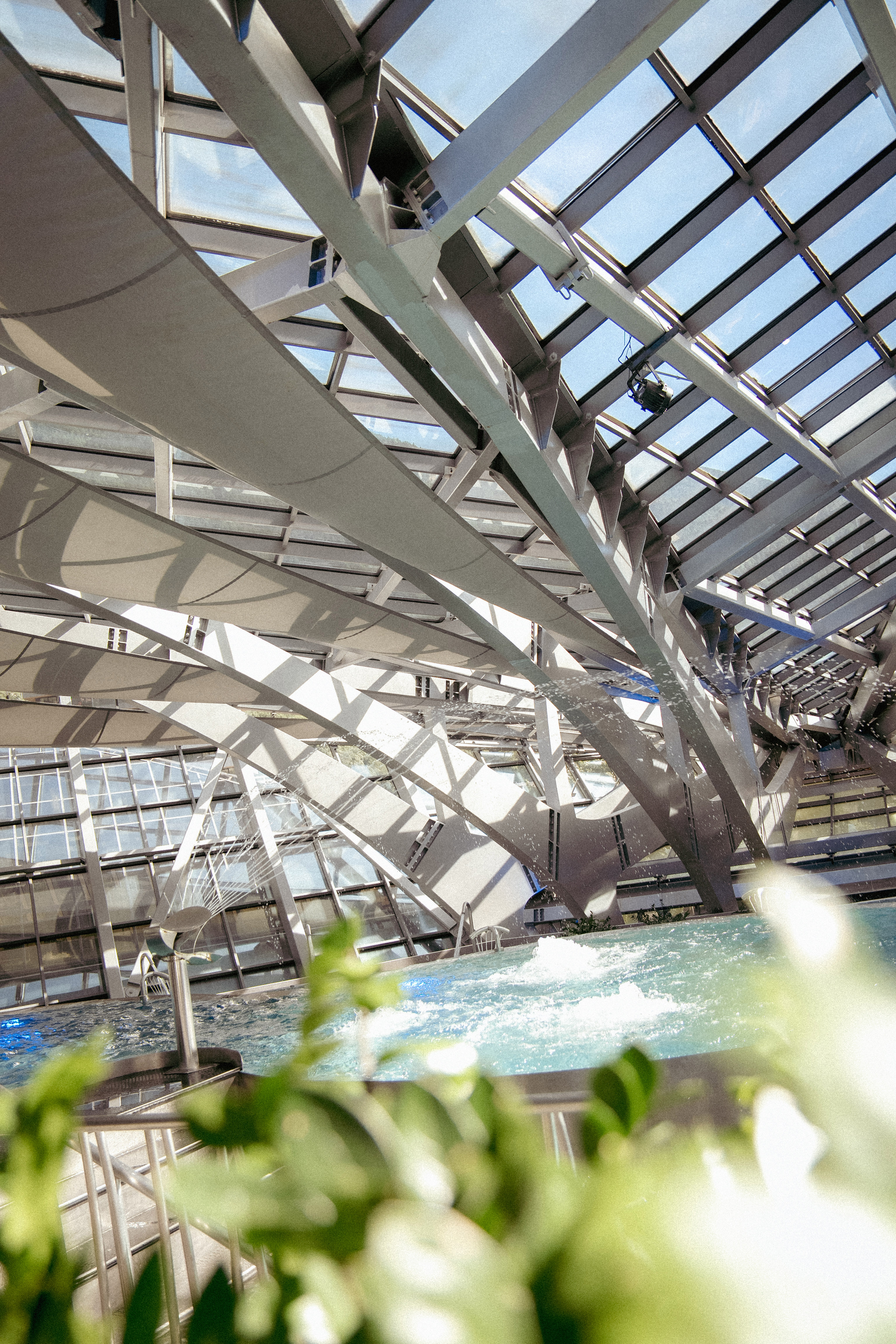 Arquitectura moderna: techo de cristal y acero sobre piscina con luz natural.