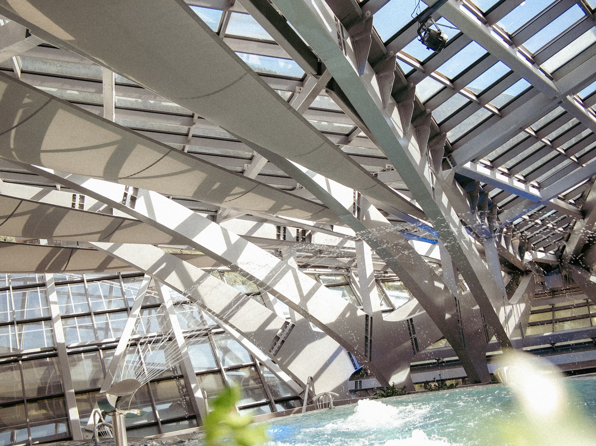 Arquitectura moderna: techo de cristal y acero sobre piscina con luz natural.