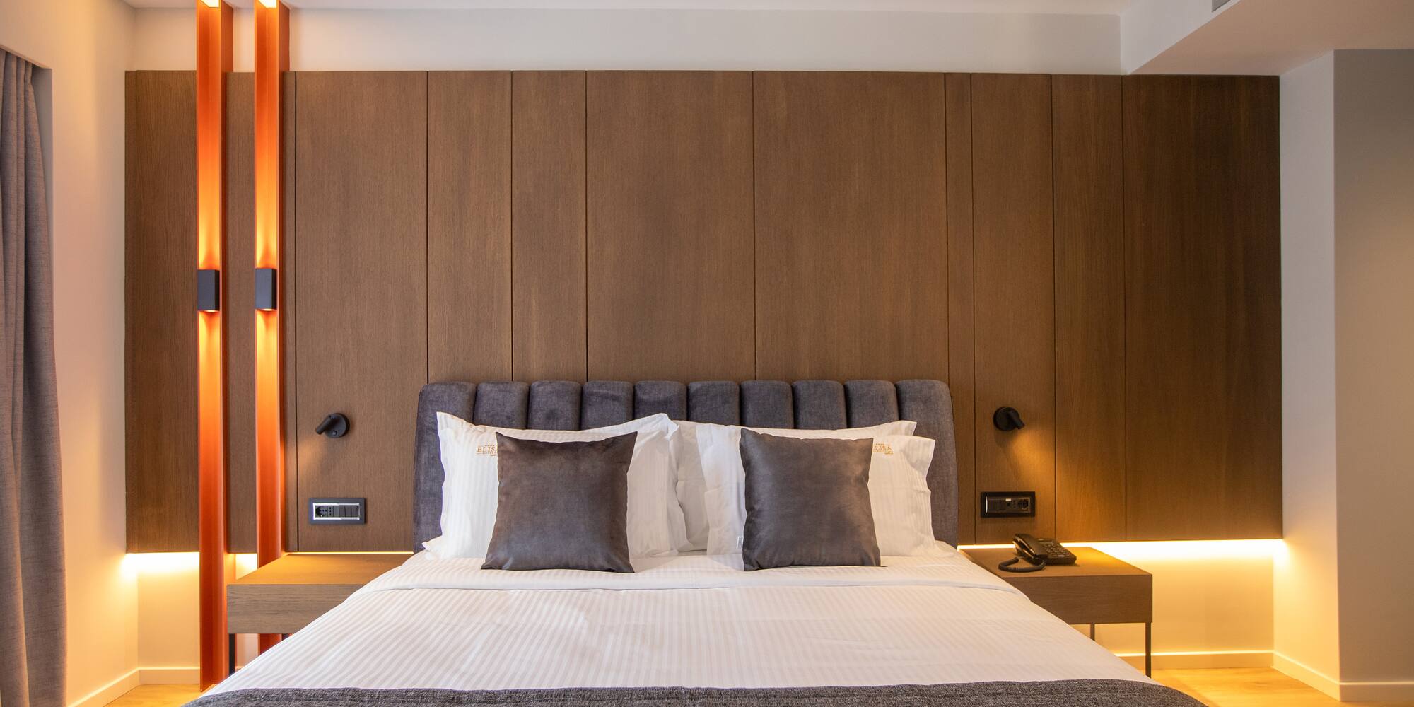 a bed with pillows and a table in front of a wood wall