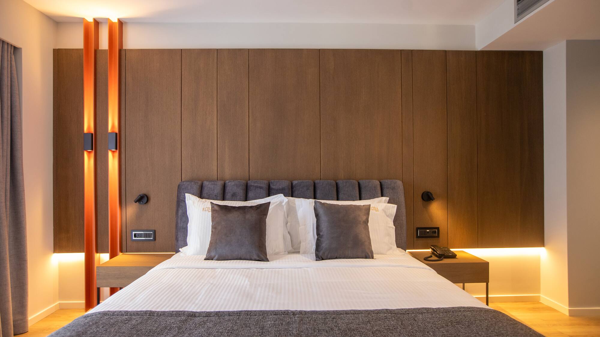 a bed with pillows and a table in front of a wood wall