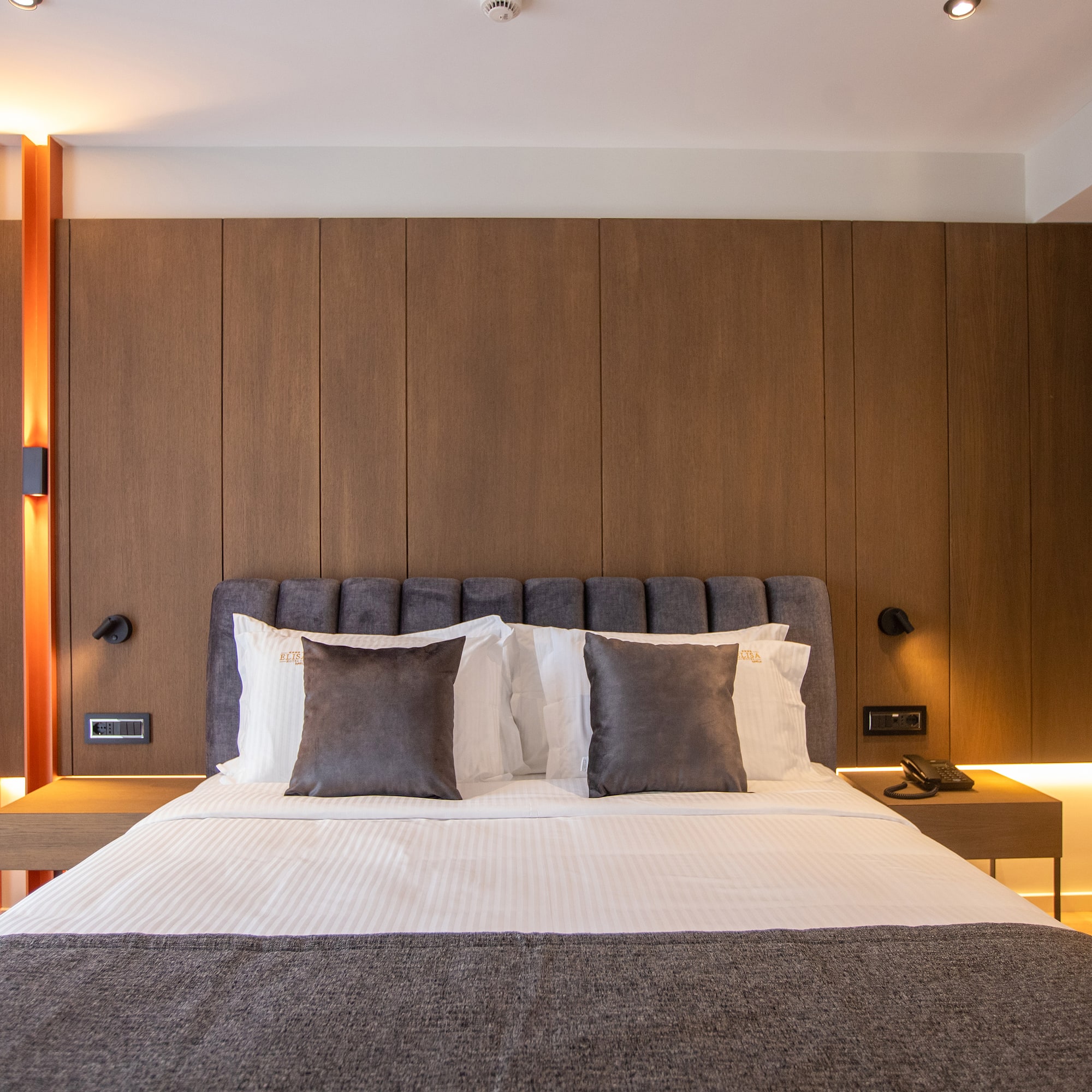 a bed with pillows and a table in front of a wood wall