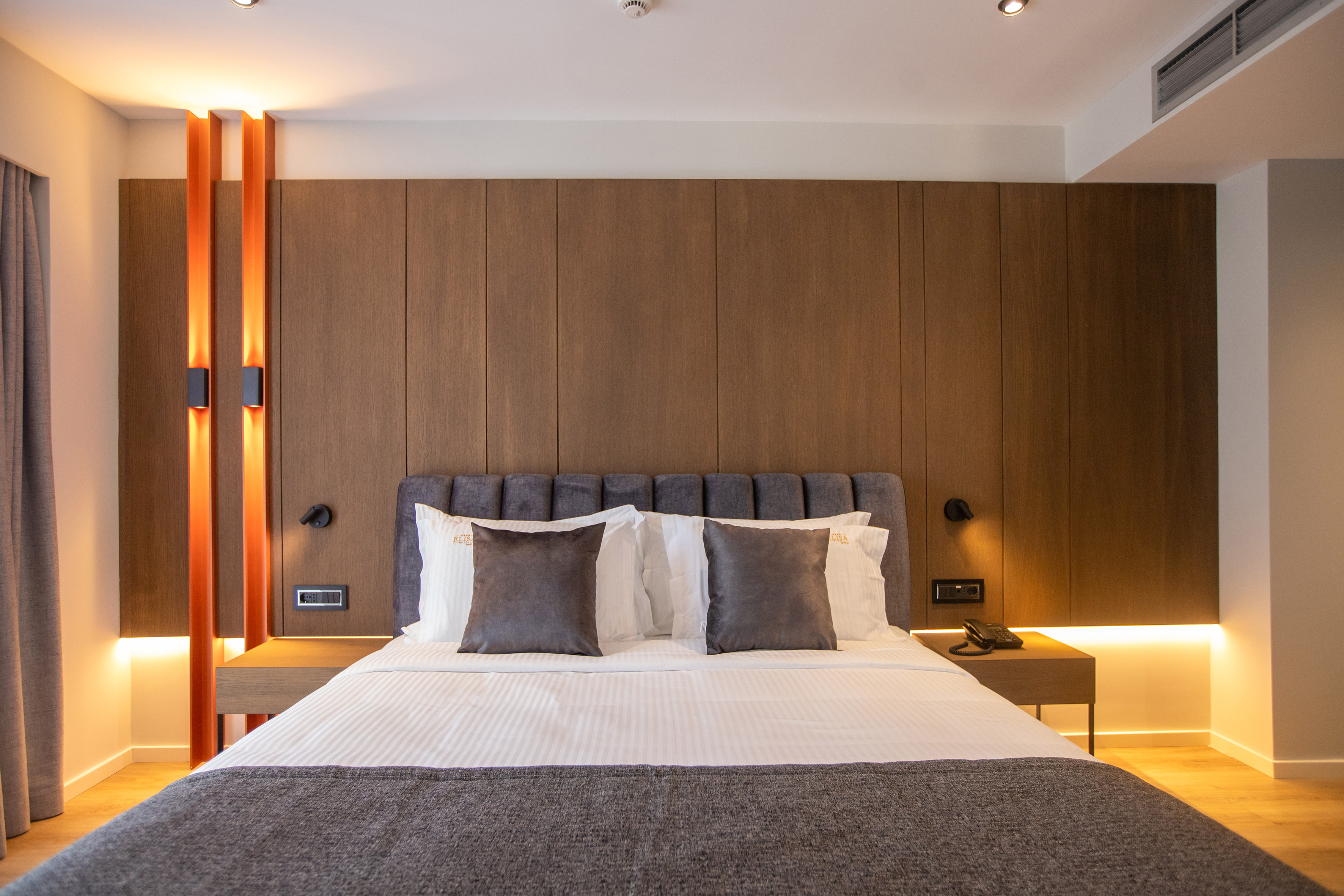 a bed with pillows and a table in front of a wood wall