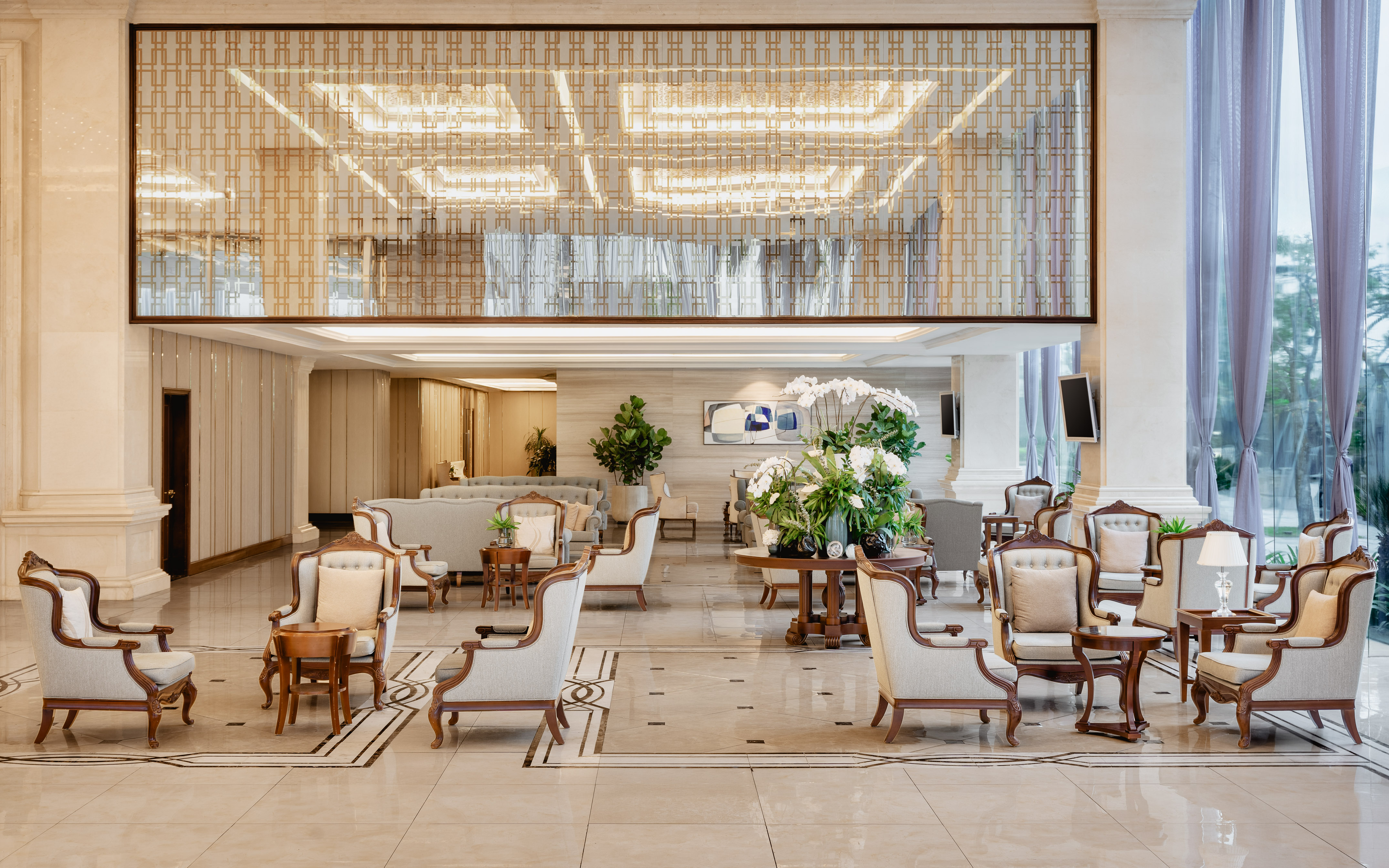 Elegant hotel lobby lounge with classic seating, large windows, and ornate ceiling.