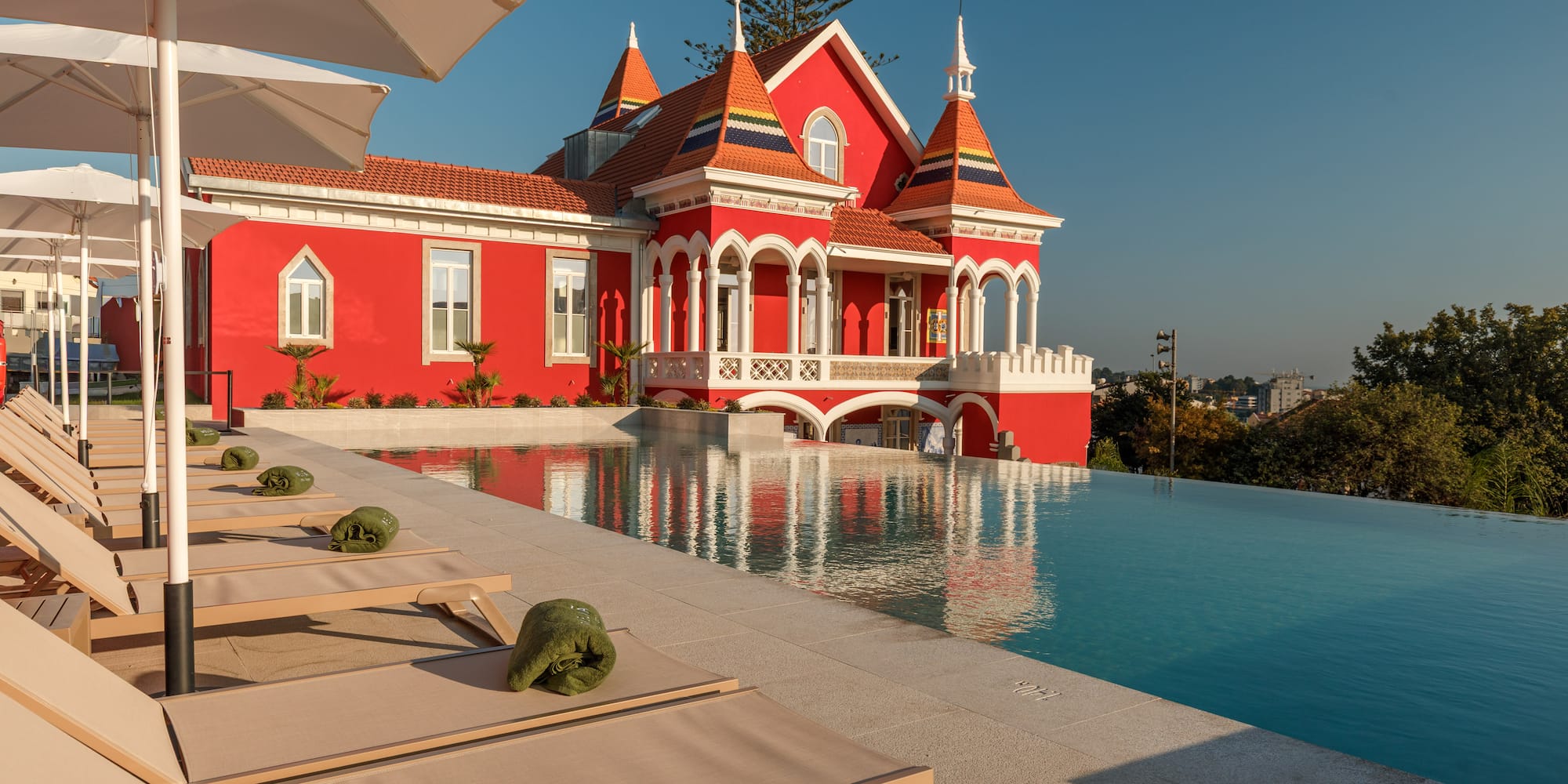 a pool with lounge chairs and a red house