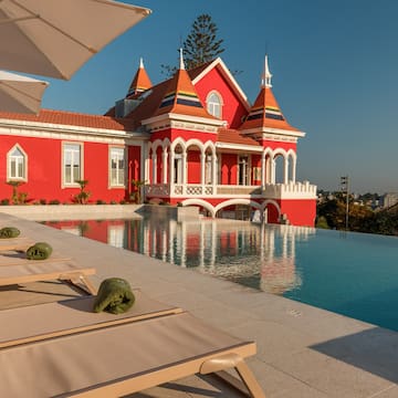 a pool with lounge chairs and a red house