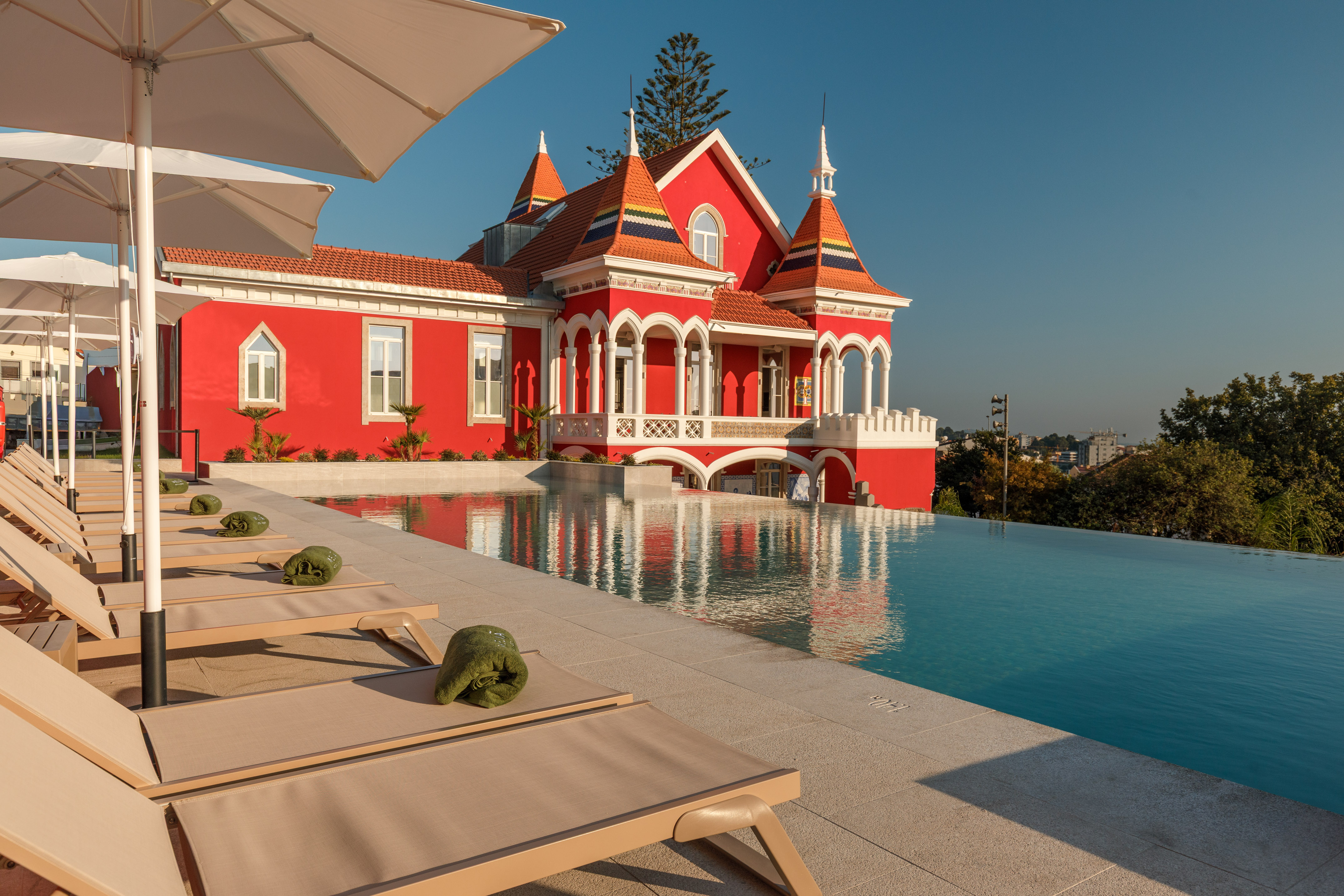 a pool with lounge chairs and a red house