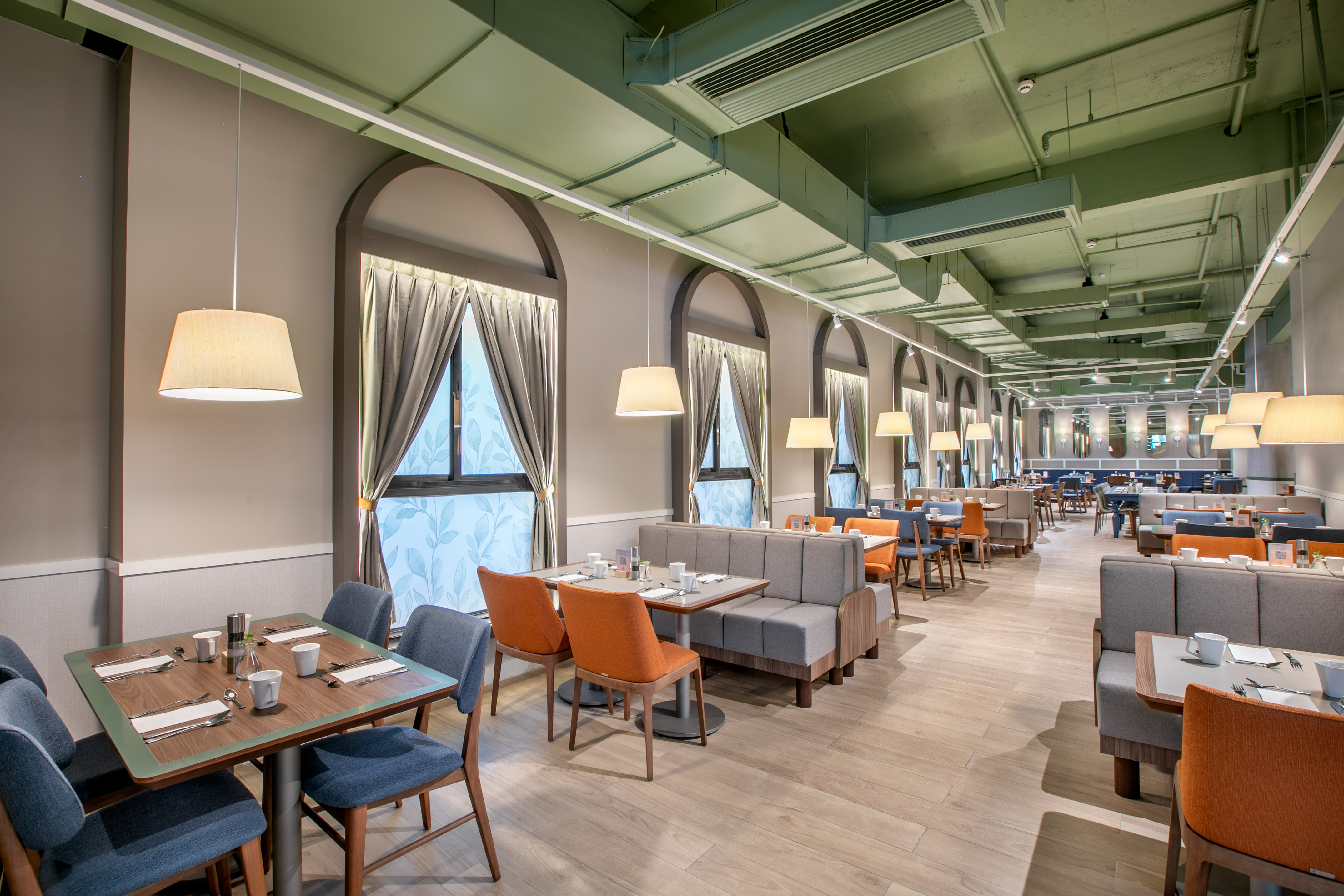 Modern restaurant dining room, booth seating, arched windows, pendant lights.