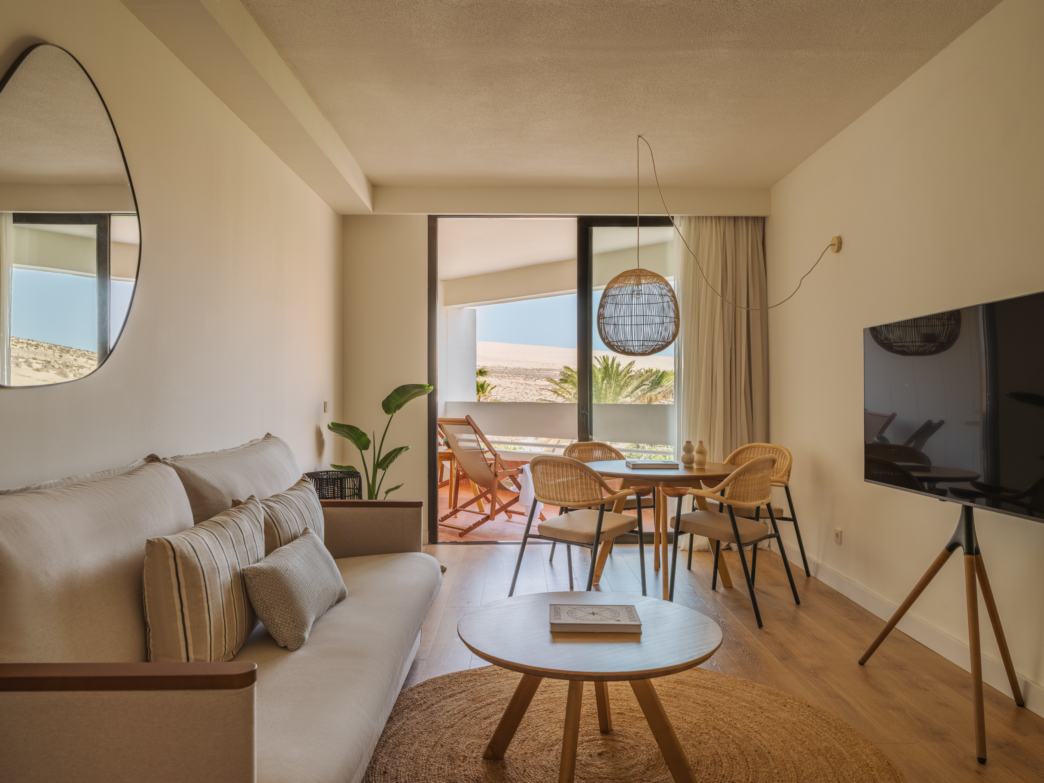 Modern suite living/dining room, balcony with desert dune view.