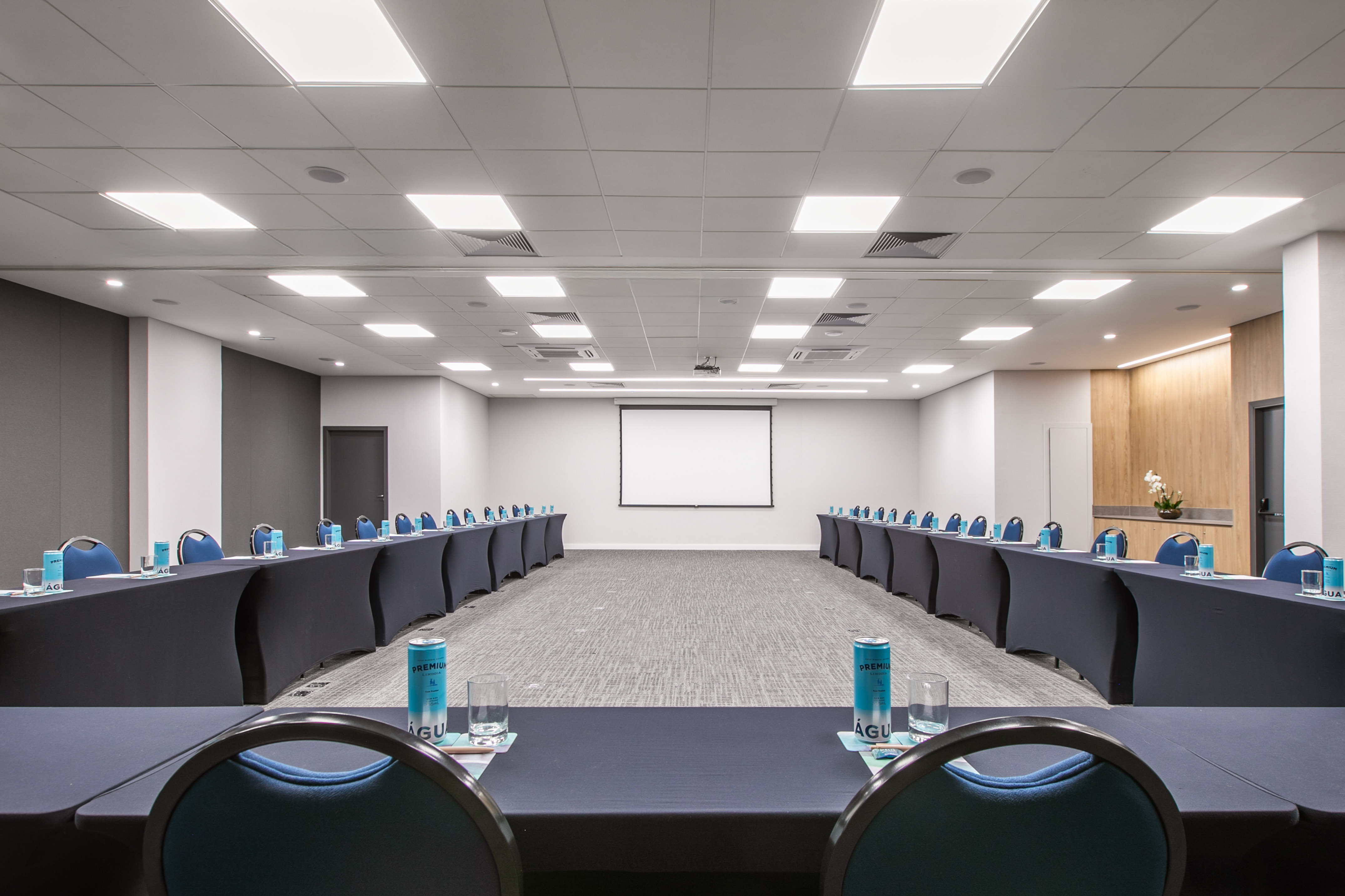 U-shaped conference room setup with blue chairs and projector screen.