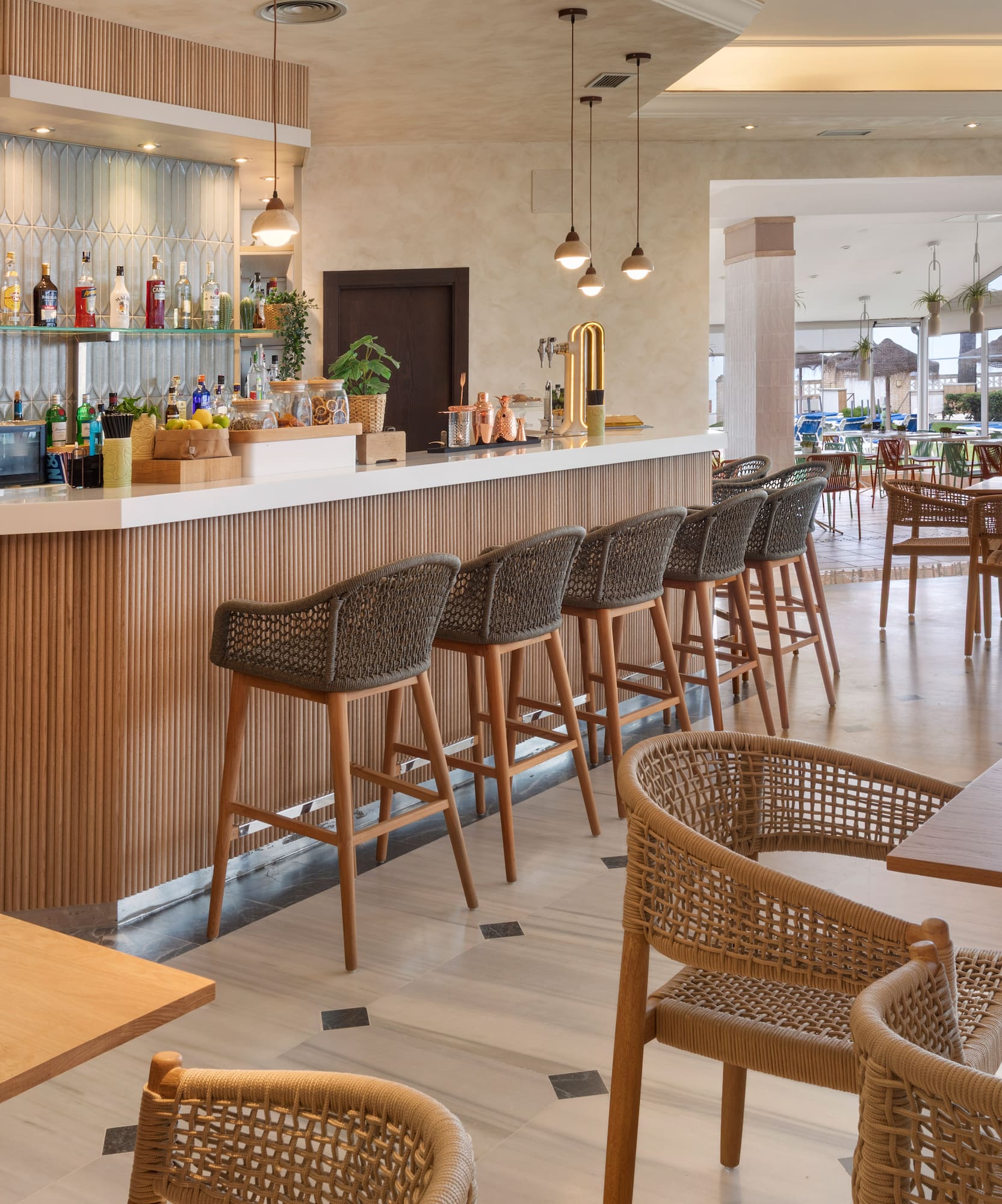 Modern resort bar with fluted wood, woven bar stools, and dining lounge.