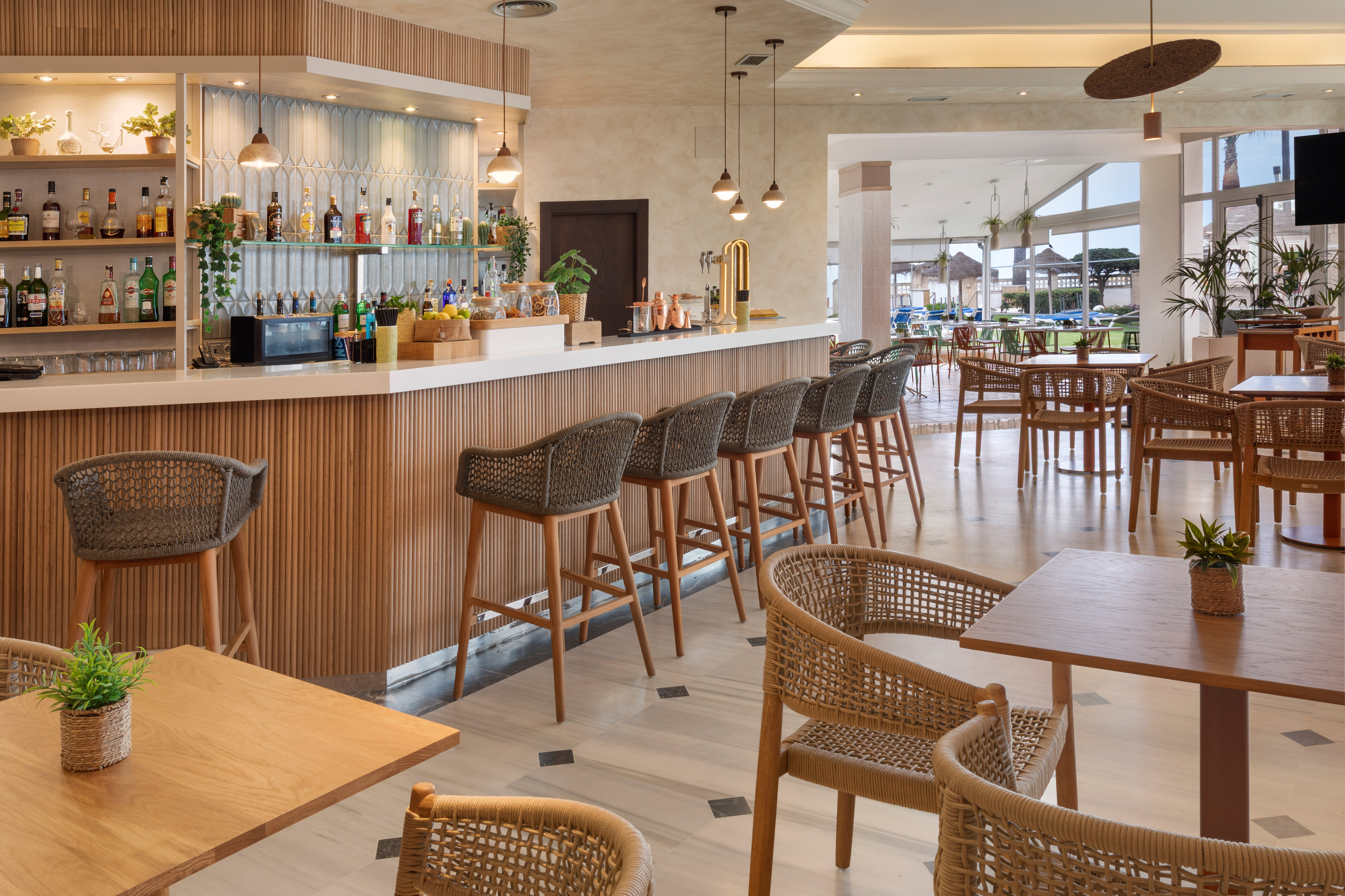Modern resort bar with fluted wood, woven bar stools, and dining lounge.