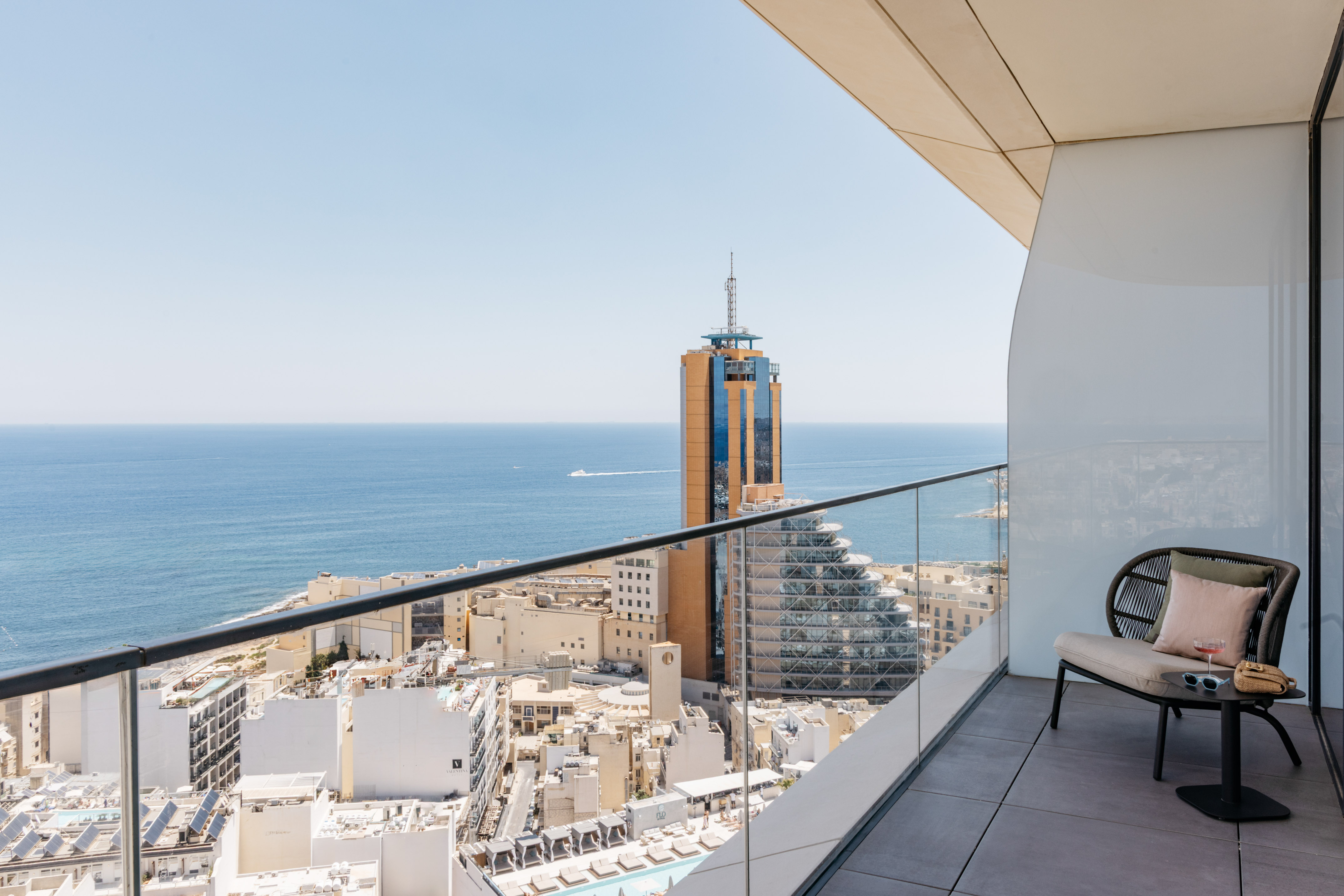 Modern high-rise balcony with panoramic sea and city views.
