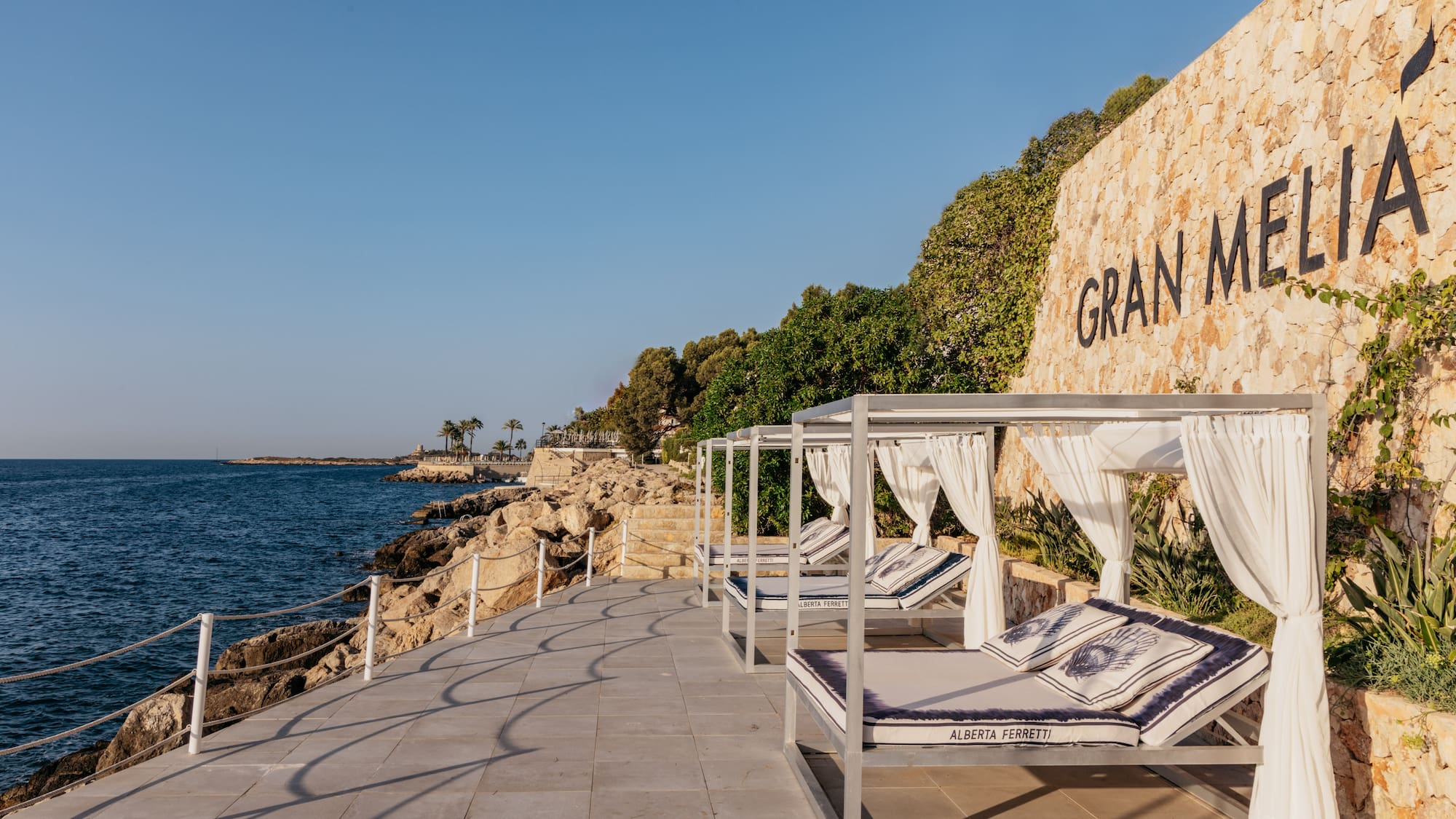 a group of beds on a deck next to a wall with trees and a sign