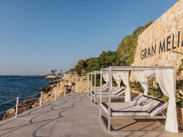 a group of beds on a deck next to a wall with trees and a sign.