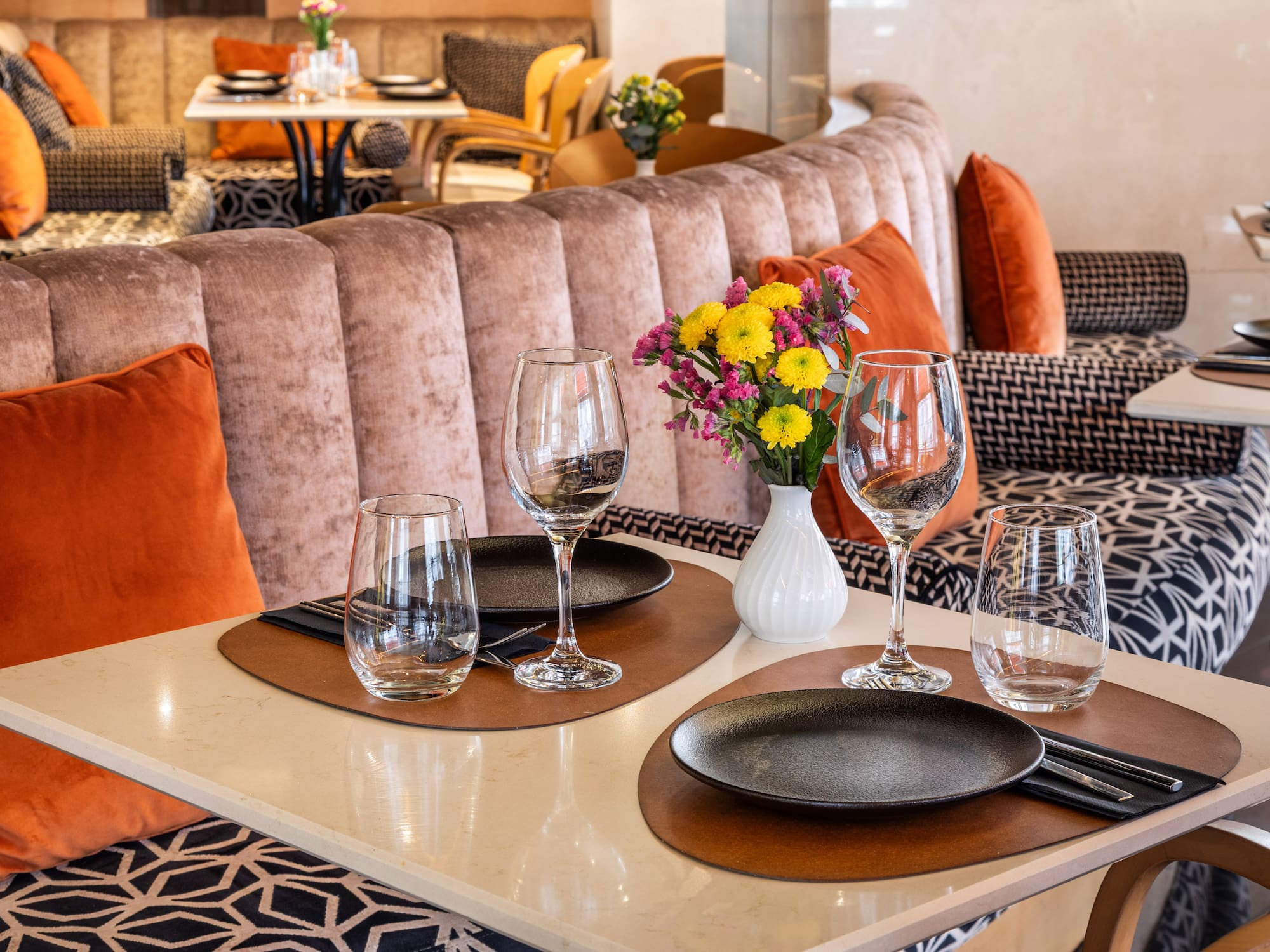 Elegant restaurant dining table with floral centerpiece and plush booth seating.