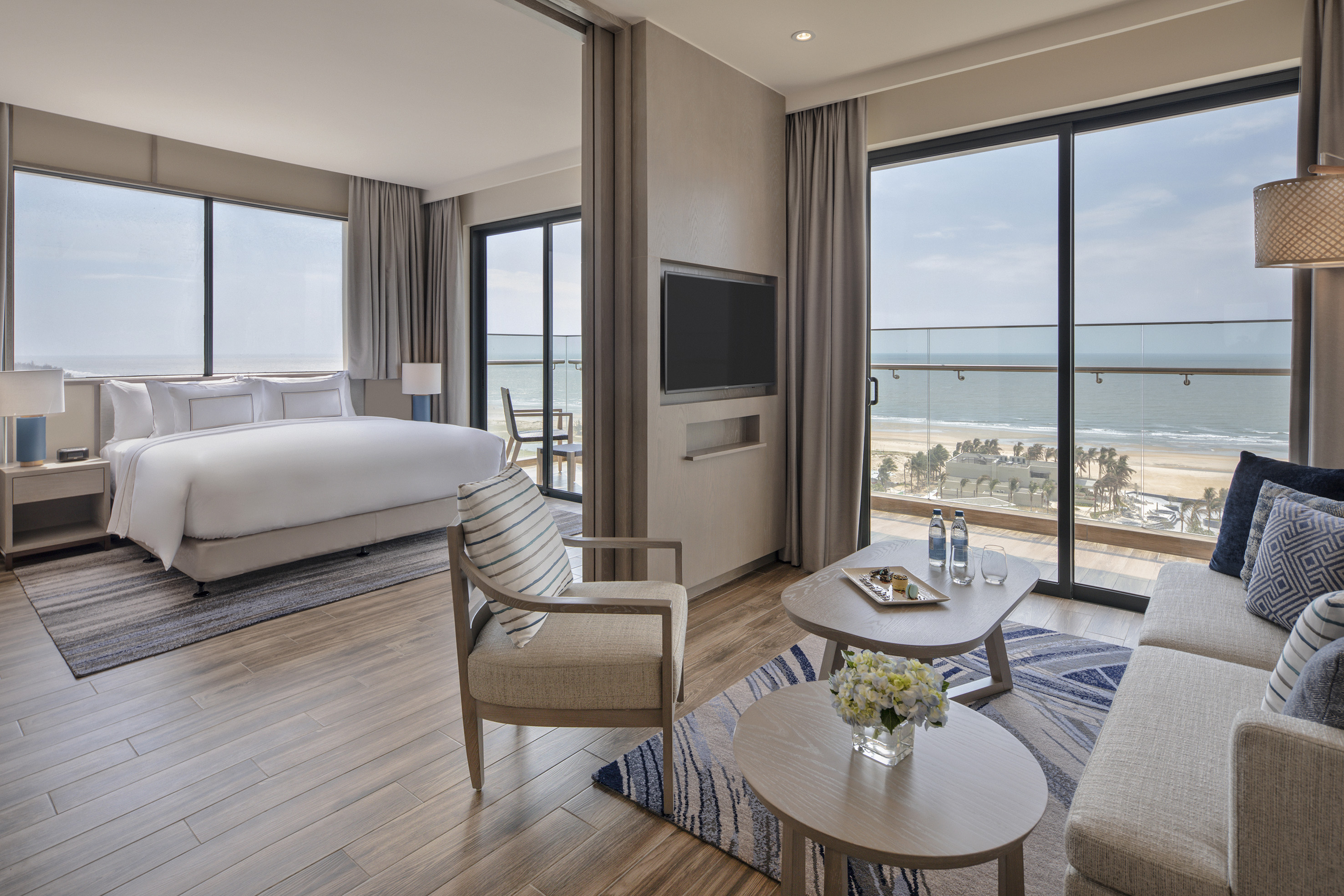 Luxury hotel suite with ocean view, modern bedroom and living area.