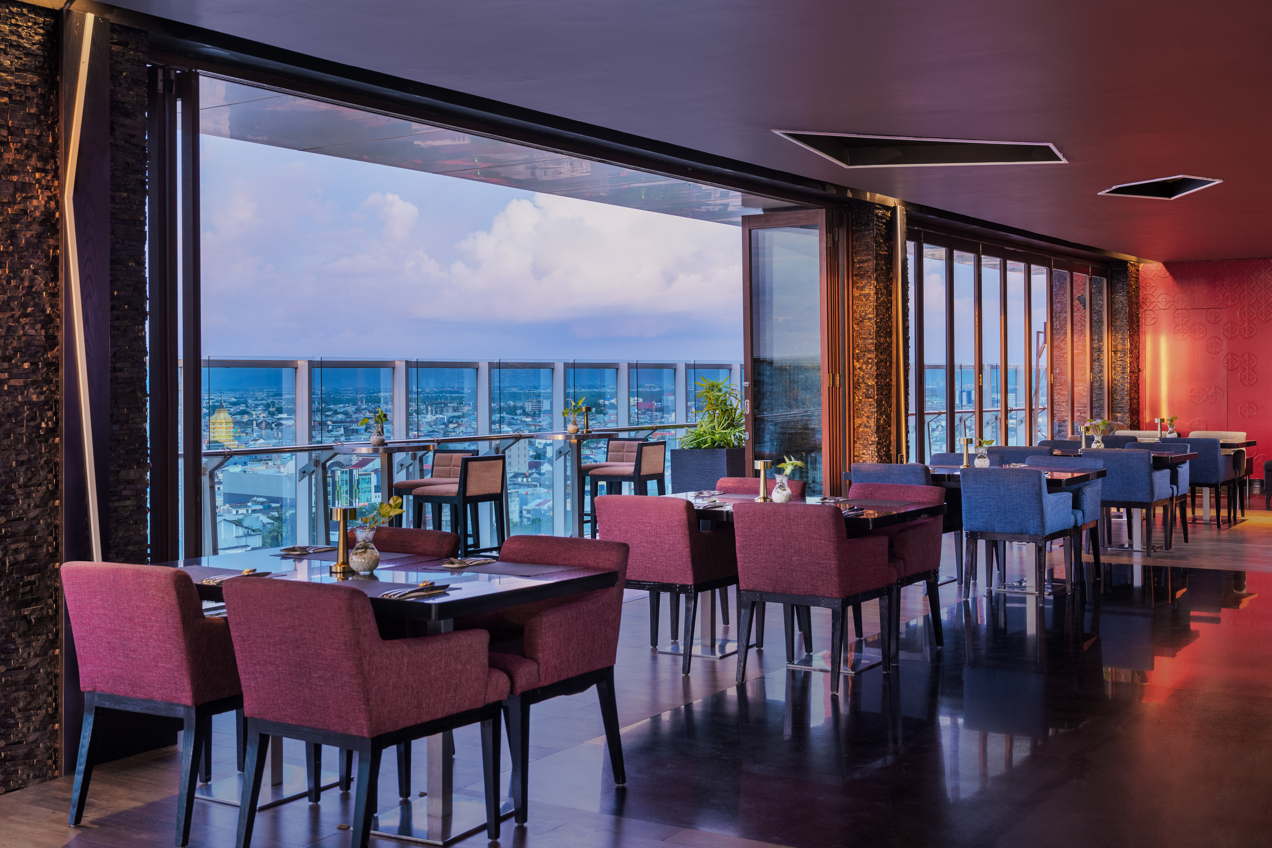 Elegant rooftop restaurant interior with panoramic city views at dusk.